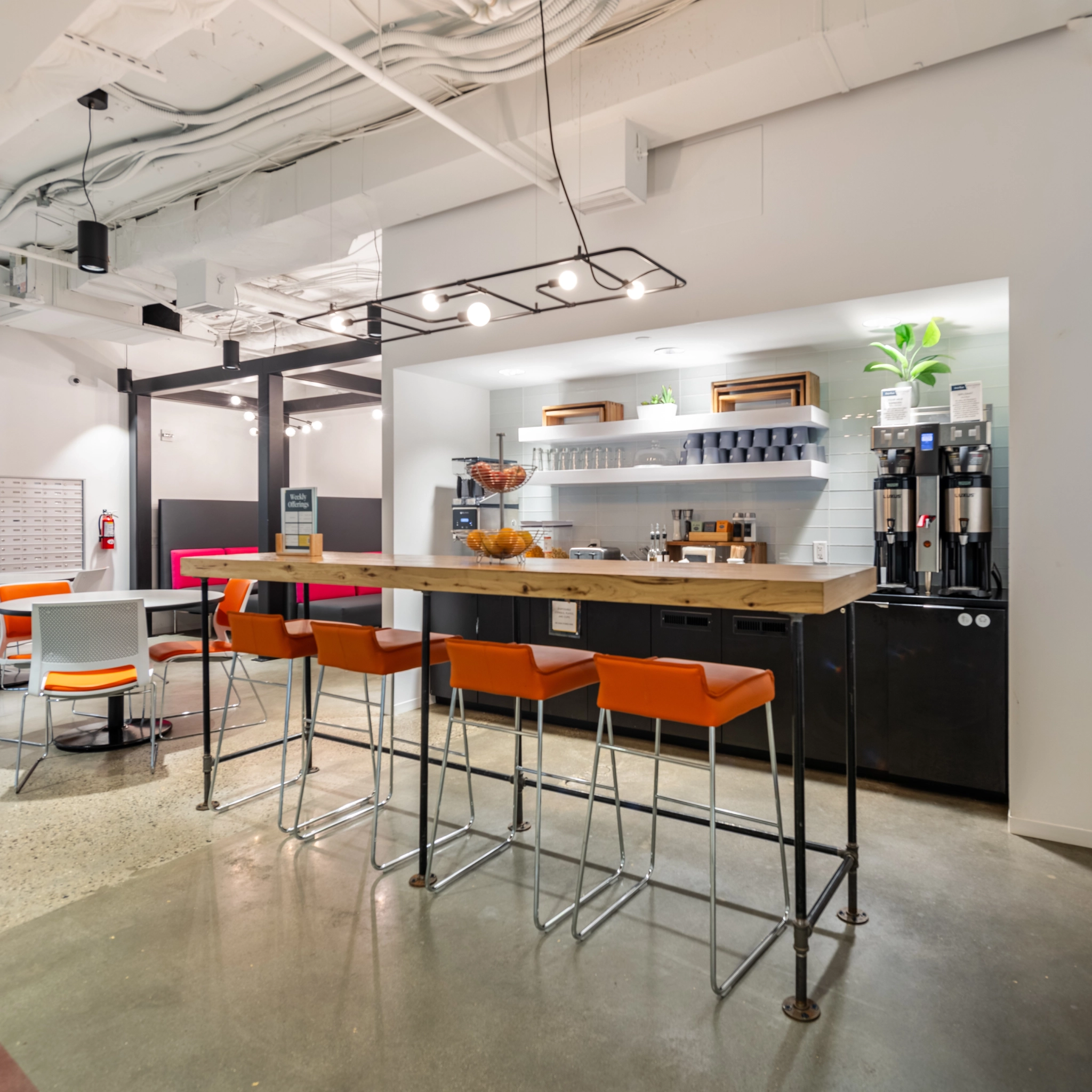 A modern kitchen with stools and a bar area, also serving as a coworking space or meeting room.