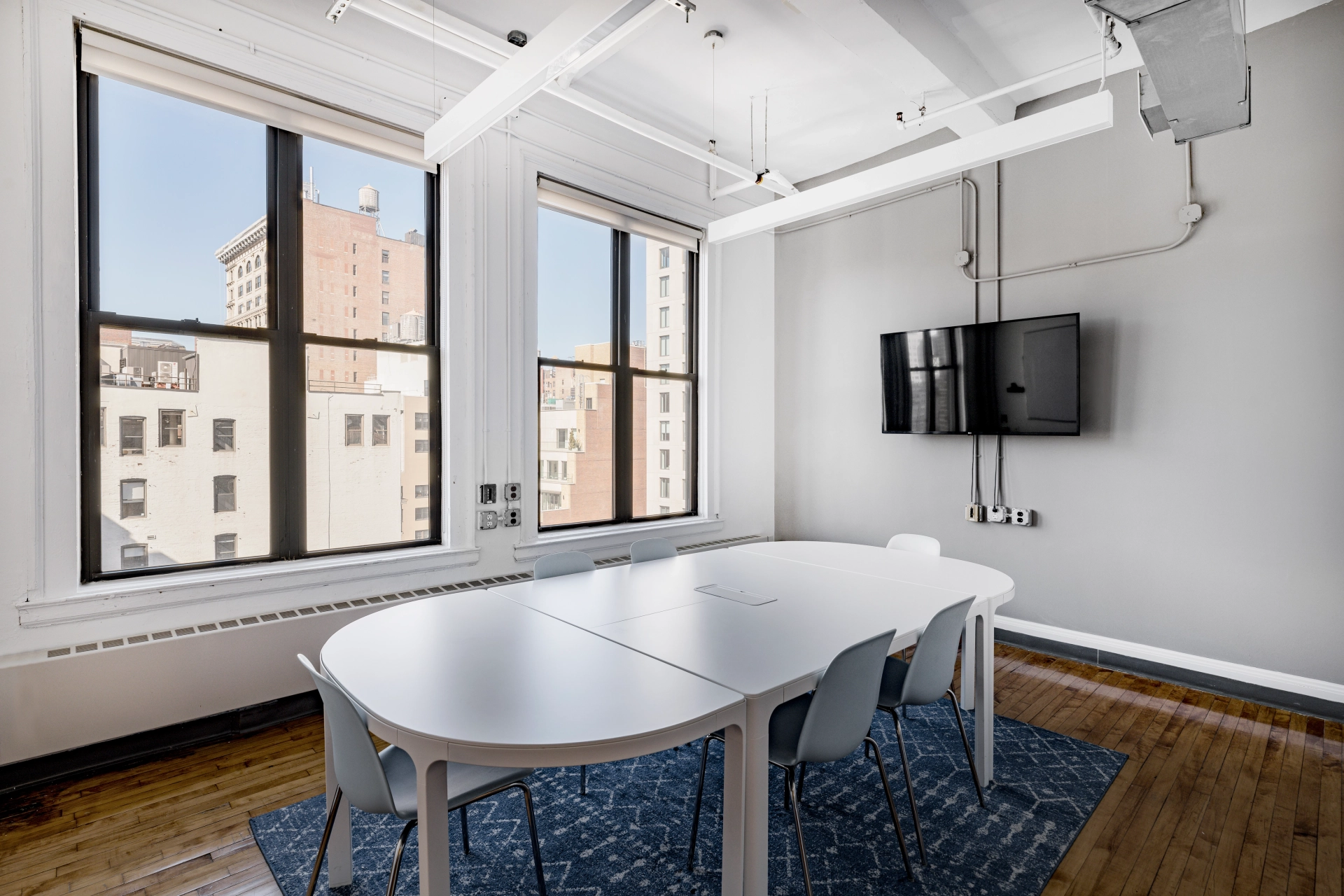 Un espace de travail de table blanche dans une salle de réunion avec de grandes fenêtres.