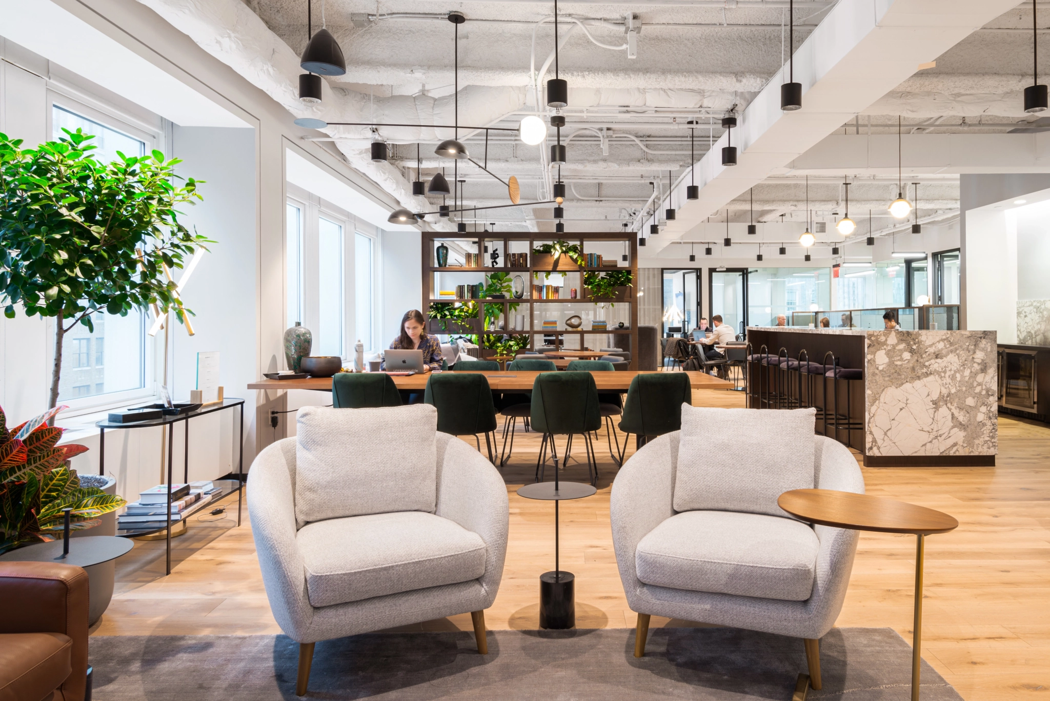 A modern coworking space in New York furnished with chairs, tables, and plants.