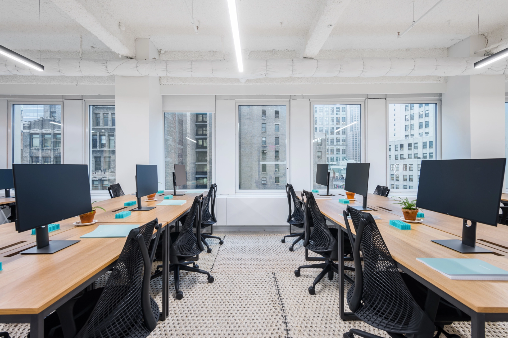An empty New York office with several coworking desks and monitors.