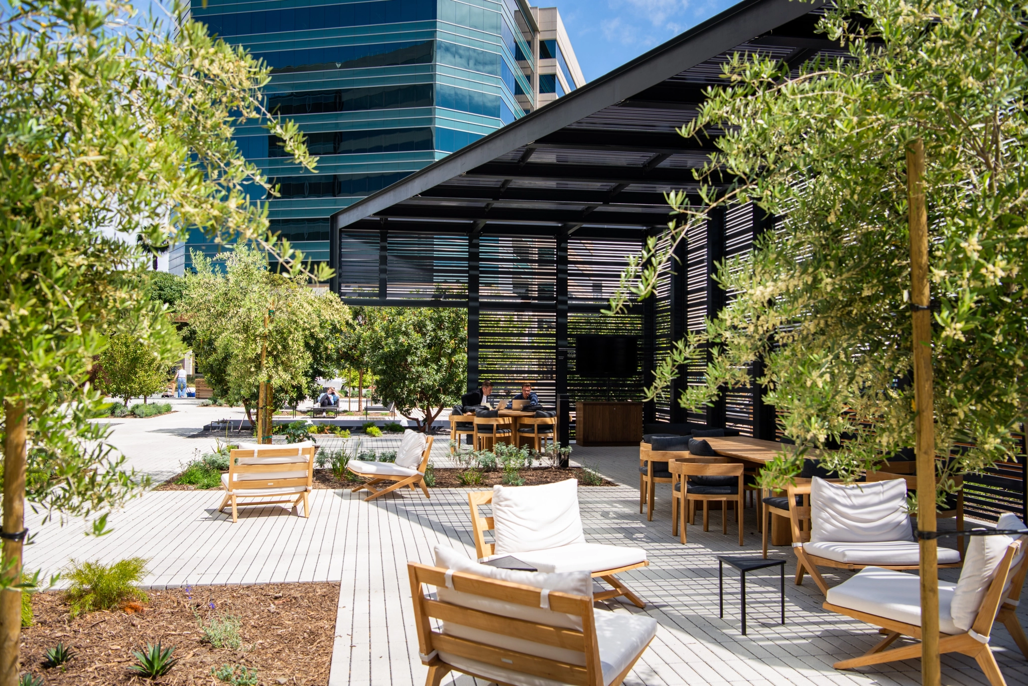 An office patio with coworking chairs and meeting room tables in front of a building.