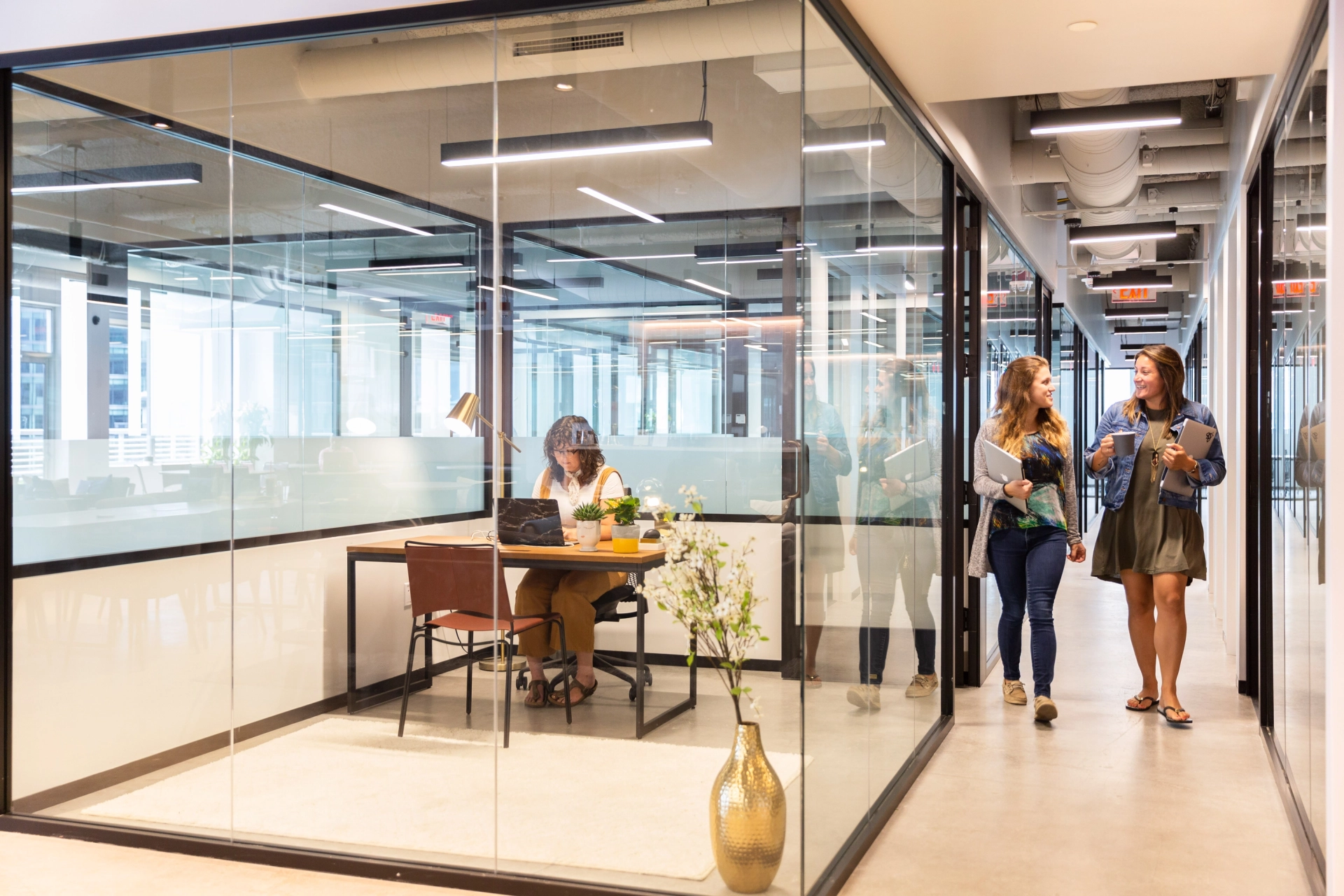 Een coworking-ruimte in Boston vol met mensen die in kantoren met glazen wanden werken.