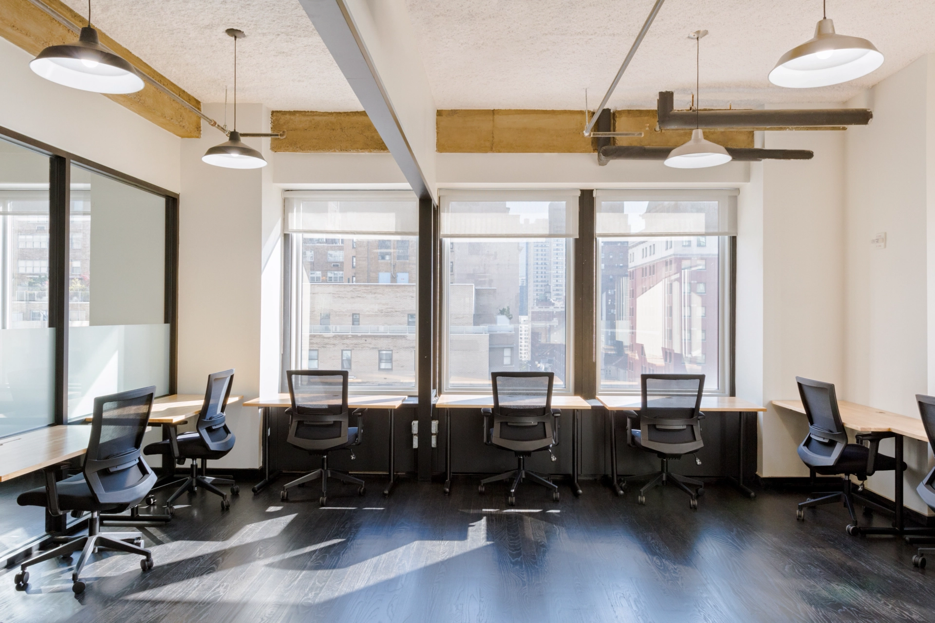 Un espace de travail de bureau à New York avec des bureaux vides, des chaises et des fenêtres.