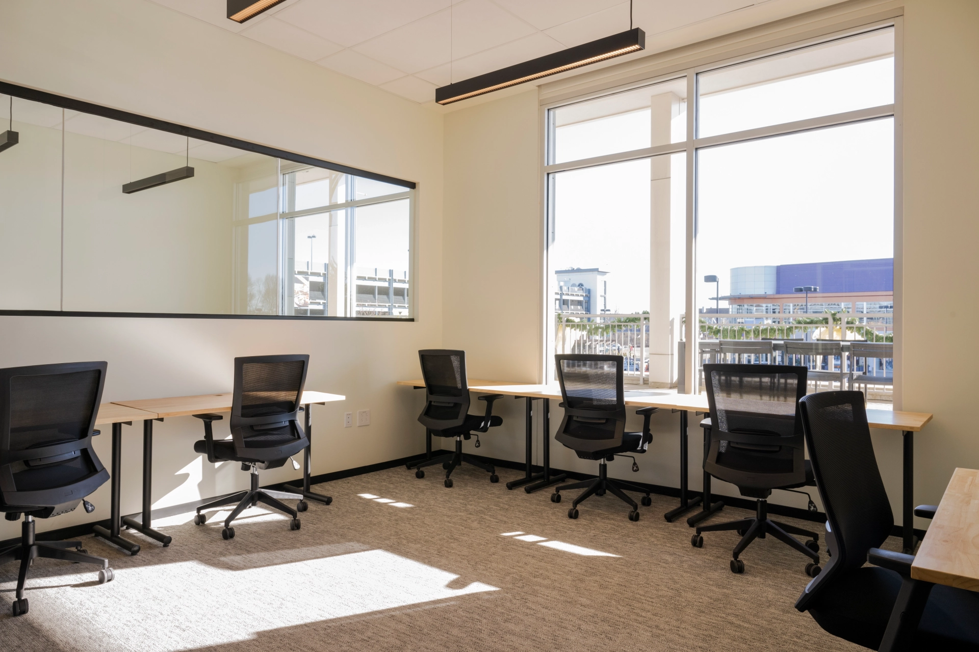 Un espace de coworking Dedham équipé de bureaux et de chaises, éclairé par la lumière naturelle d'une fenêtre.