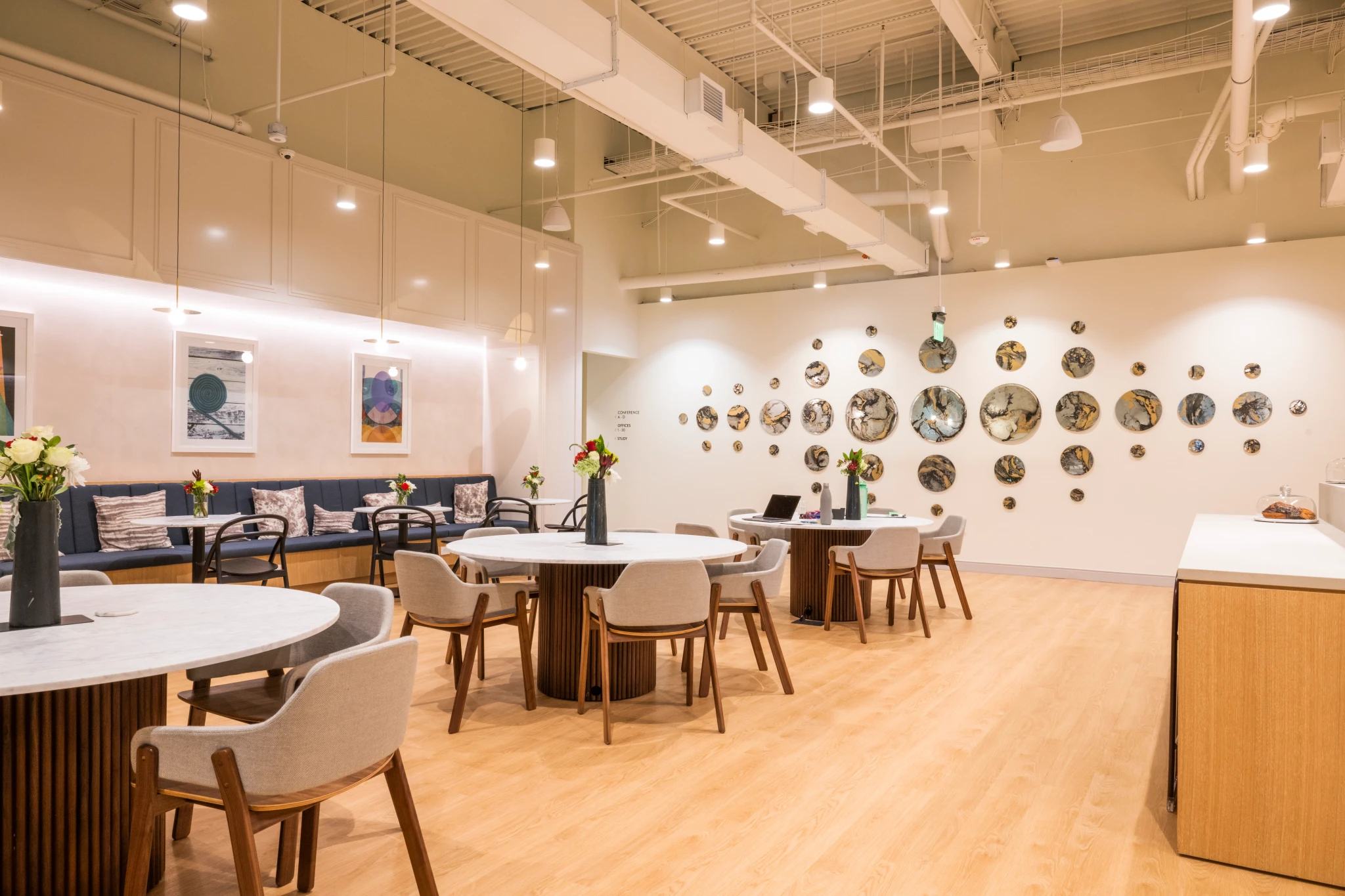 A Dedham coworking workspace featuring tables, chairs, and a wall of mirrors.