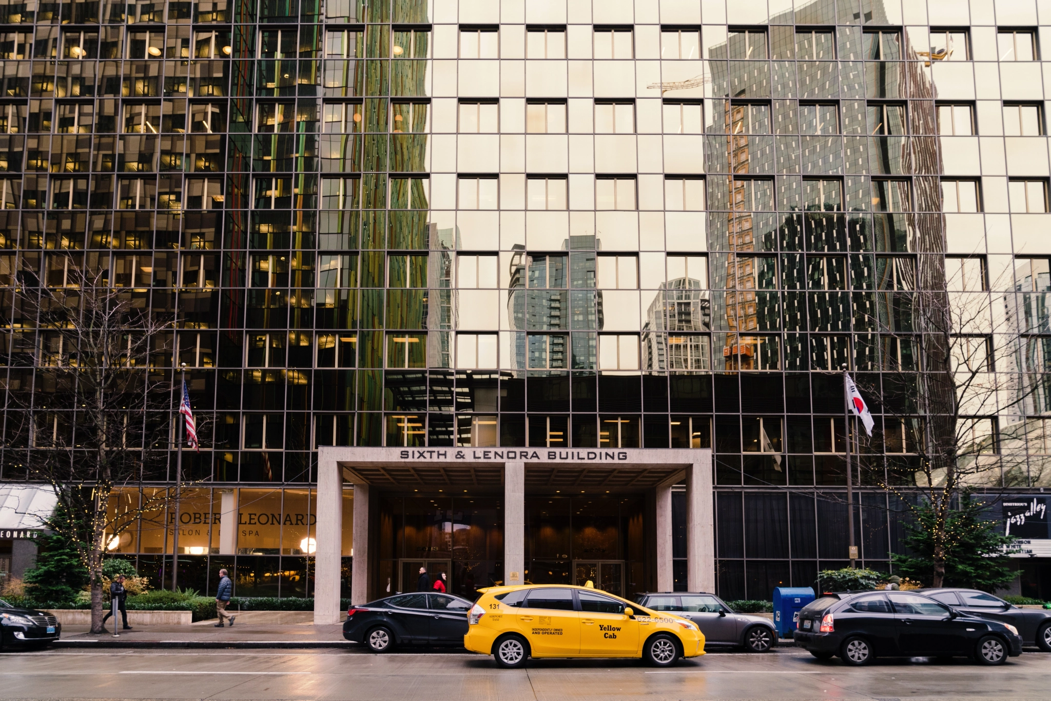 In Seattle, a yellow cab is parked in front of a tall building.