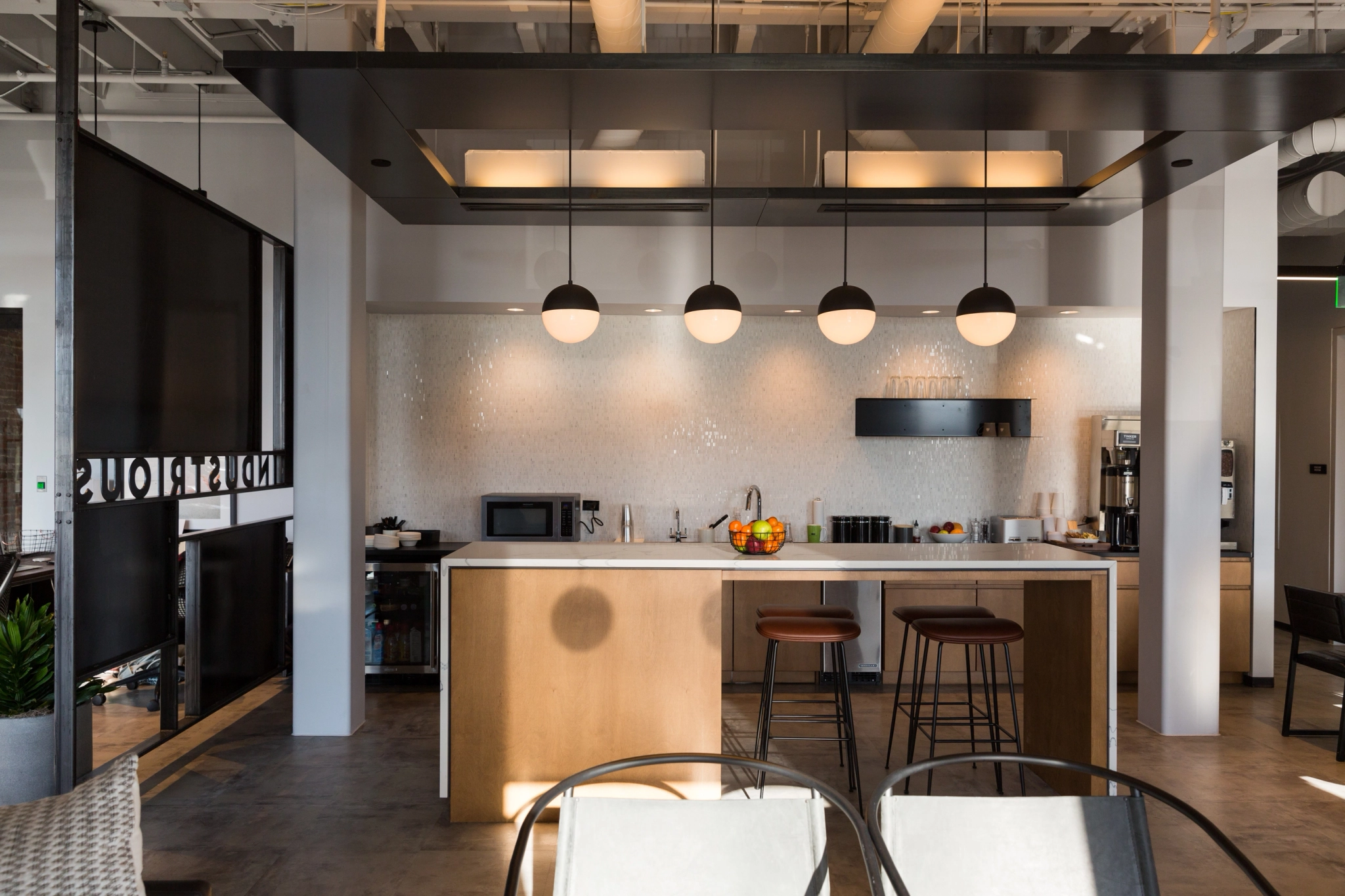 An open office workspace with a modern kitchen and dining area.