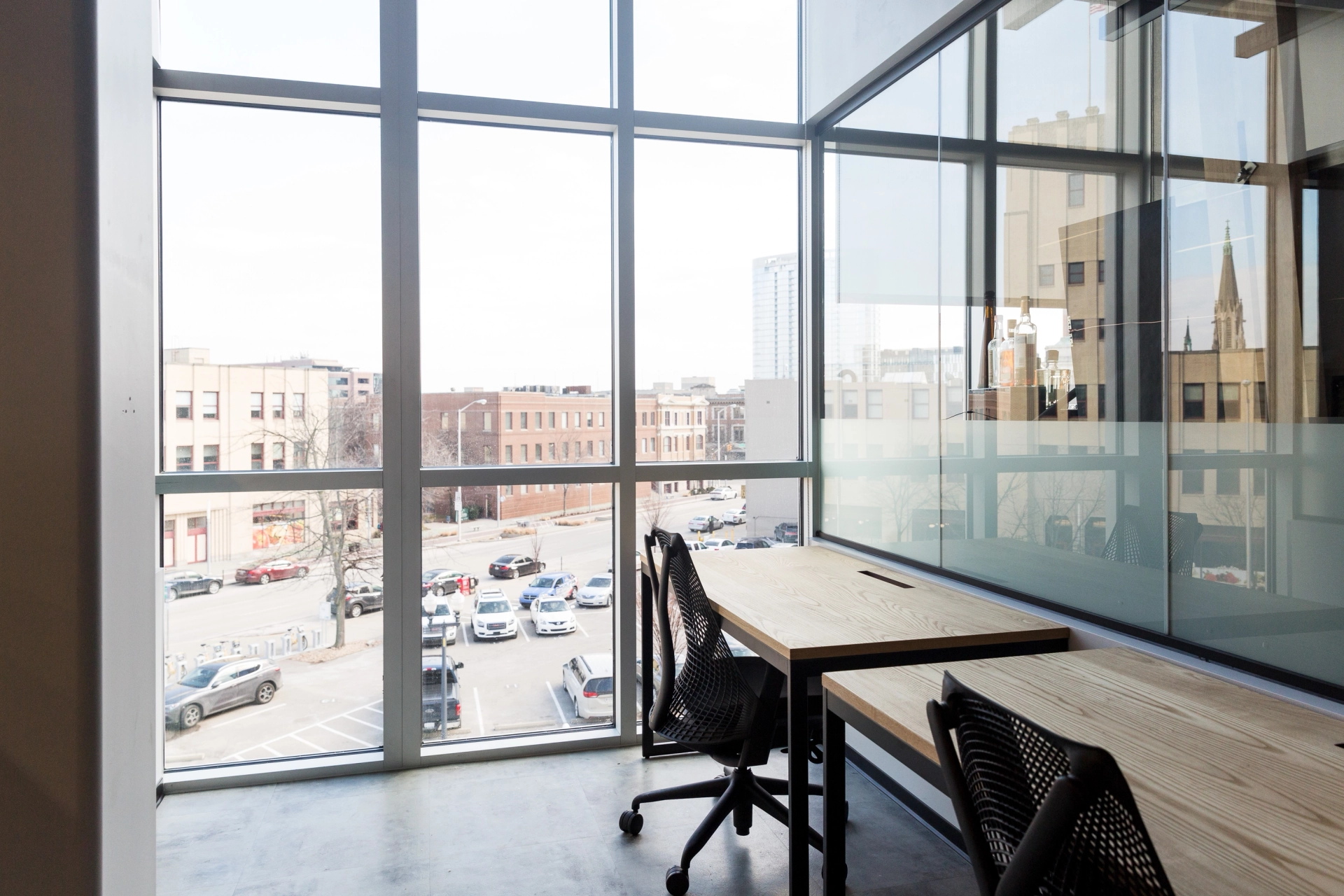 A coworking office featuring two desks and a window with a city view.