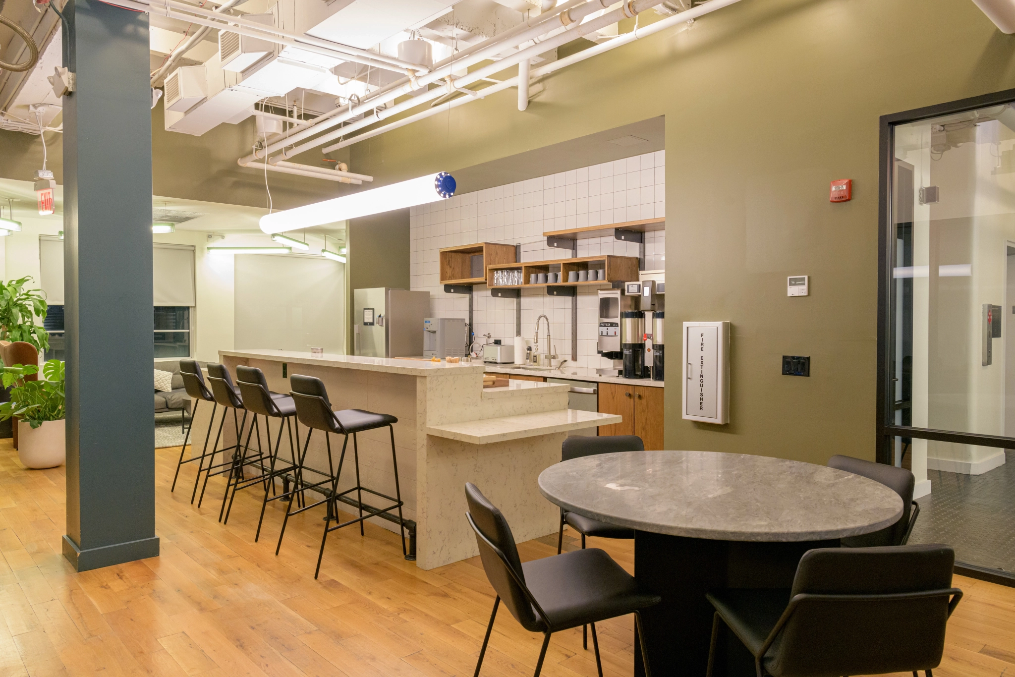 An office workspace with a table and chairs and a kitchen.