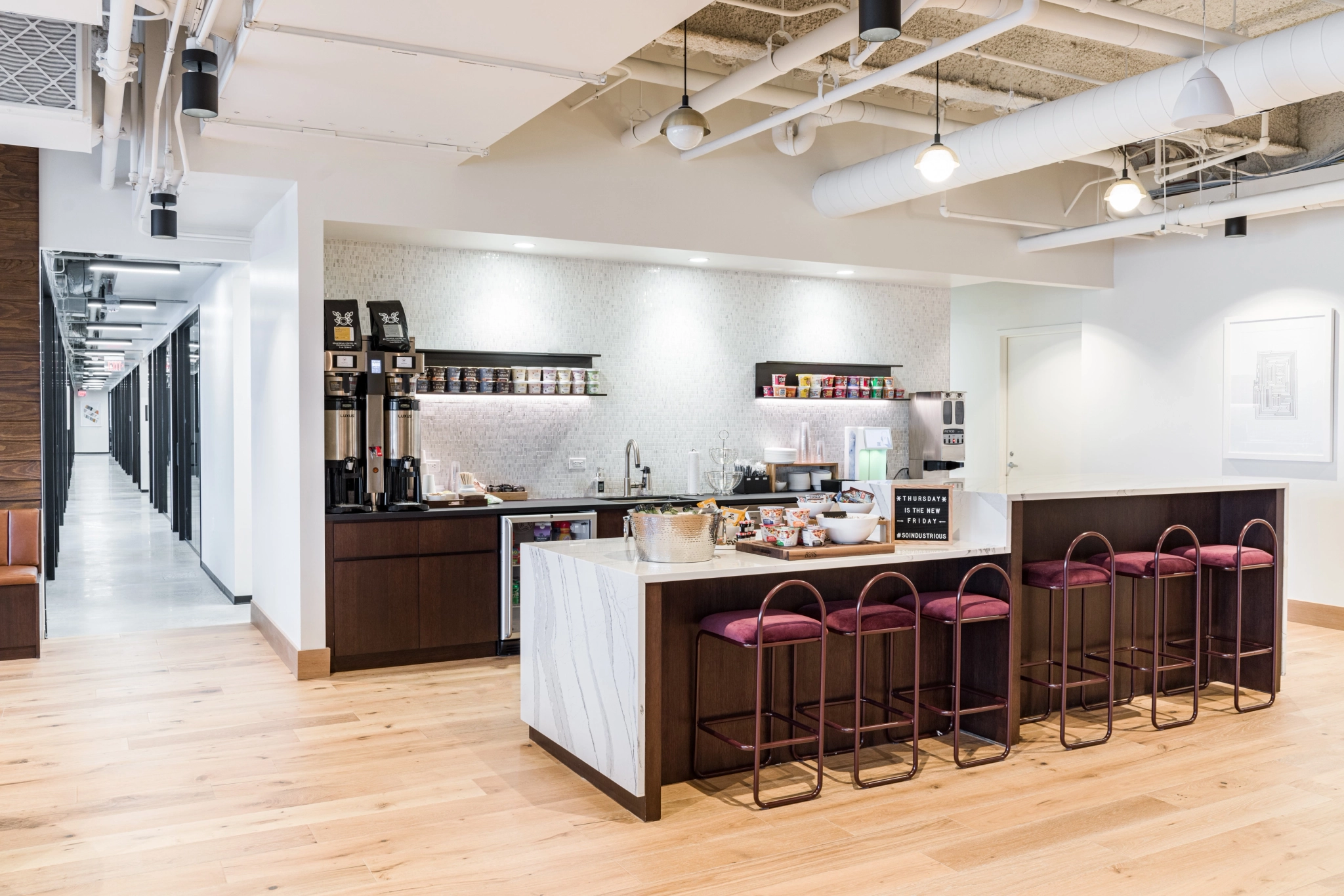 A coworking workspace with a kitchenette and bar stools.