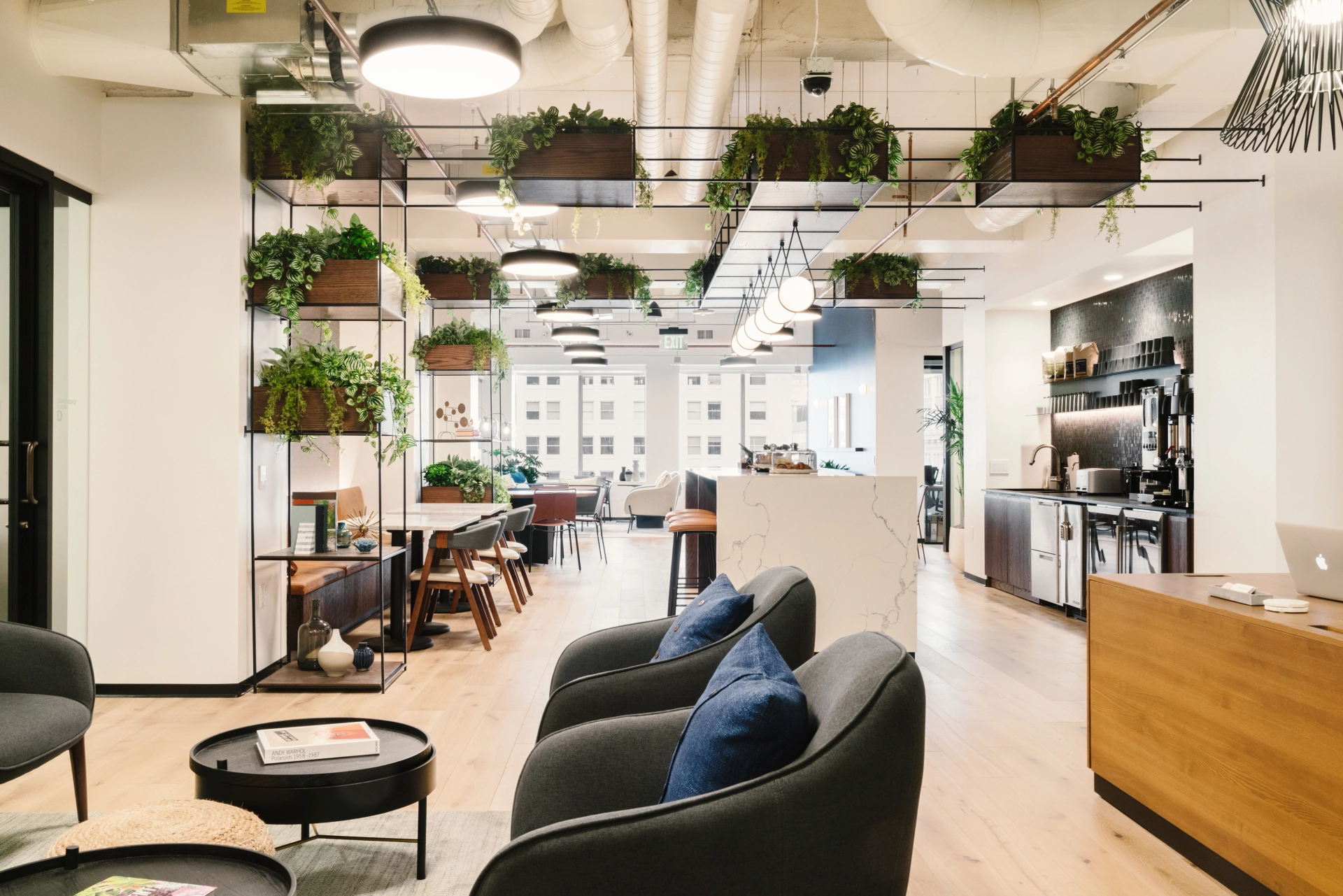 Moderne kantoorlounge en coworkingruimte met hangplanten en comfortabele stoelen.