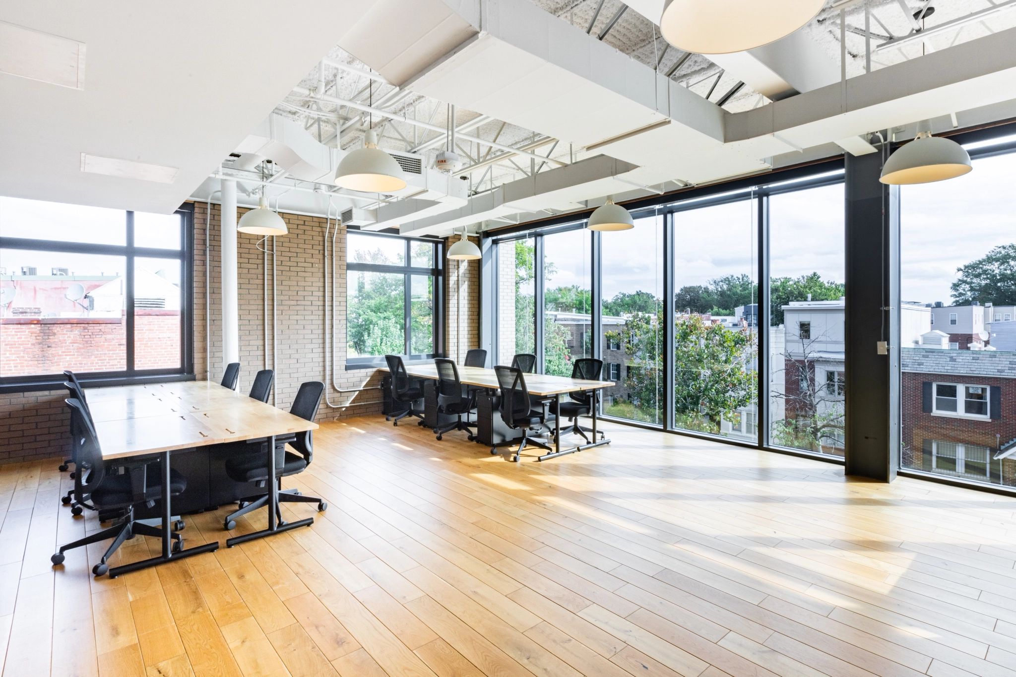 A large suite space with floor to ceiling windows and wooden floors.