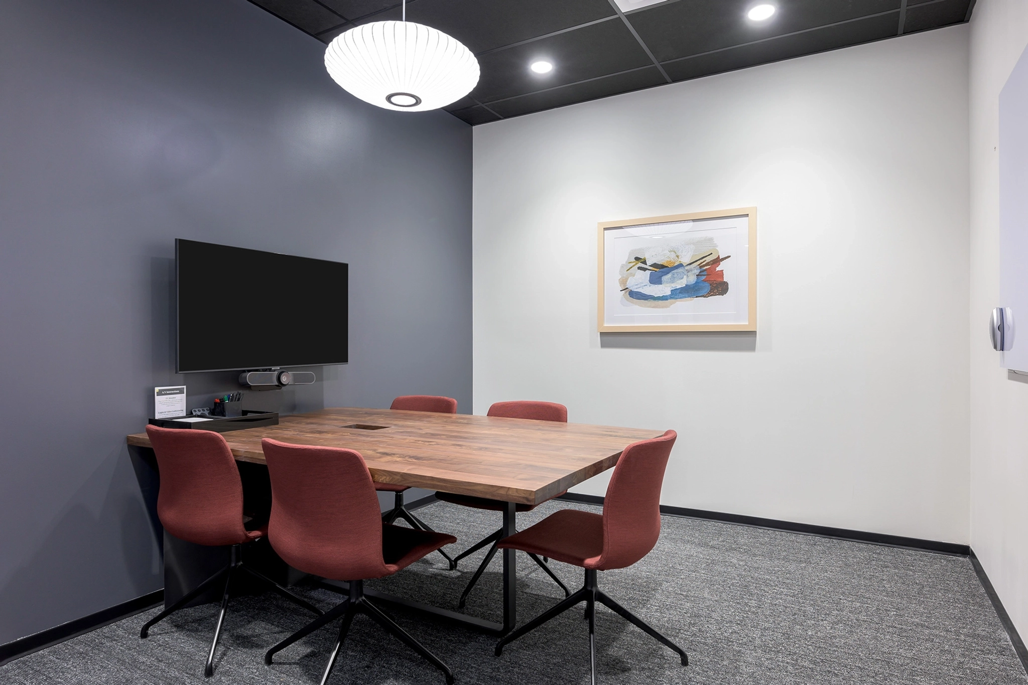 A meeting room with a table and chairs, ideal for coworking or collaborative work. It also features a TV for presentations.