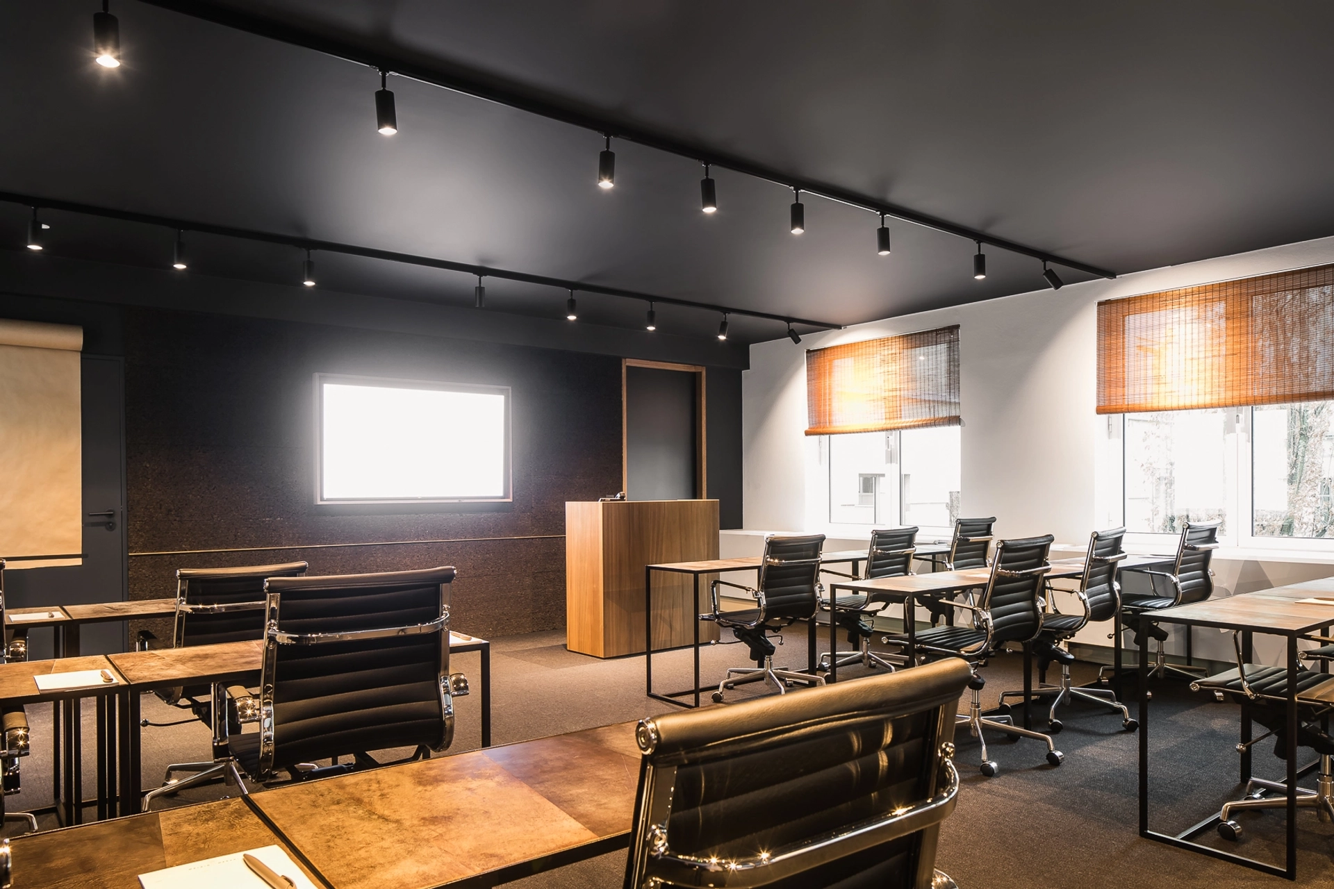 Une salle de coworking bruxelloise aux murs et chaises noirs.