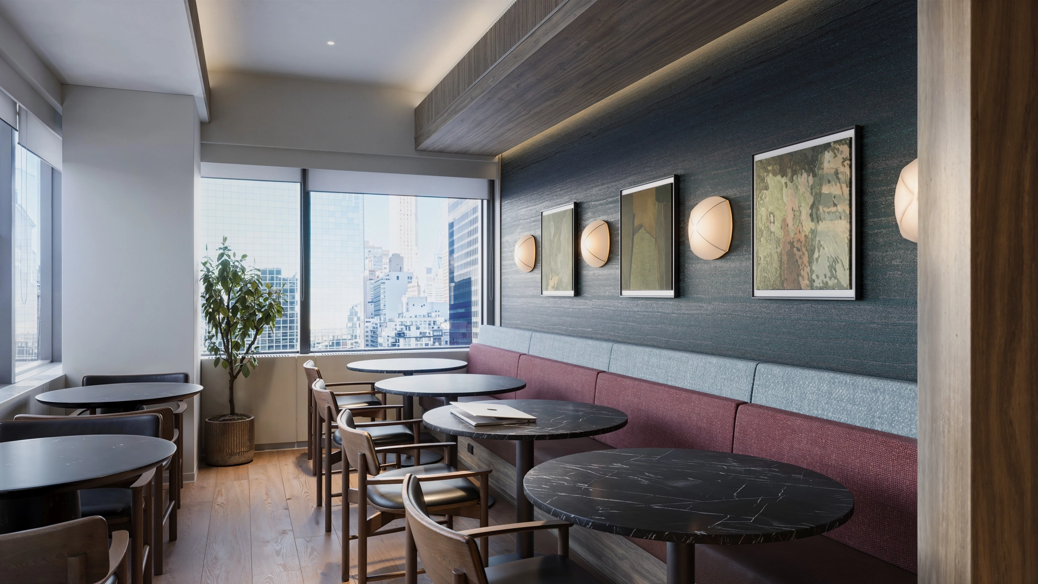 A modern cafe interior with round black tables, wooden chairs, a long cushioned bench, wall art, and large windows overlooking a New York cityscape—ideal for coworking or casual office meetings.
