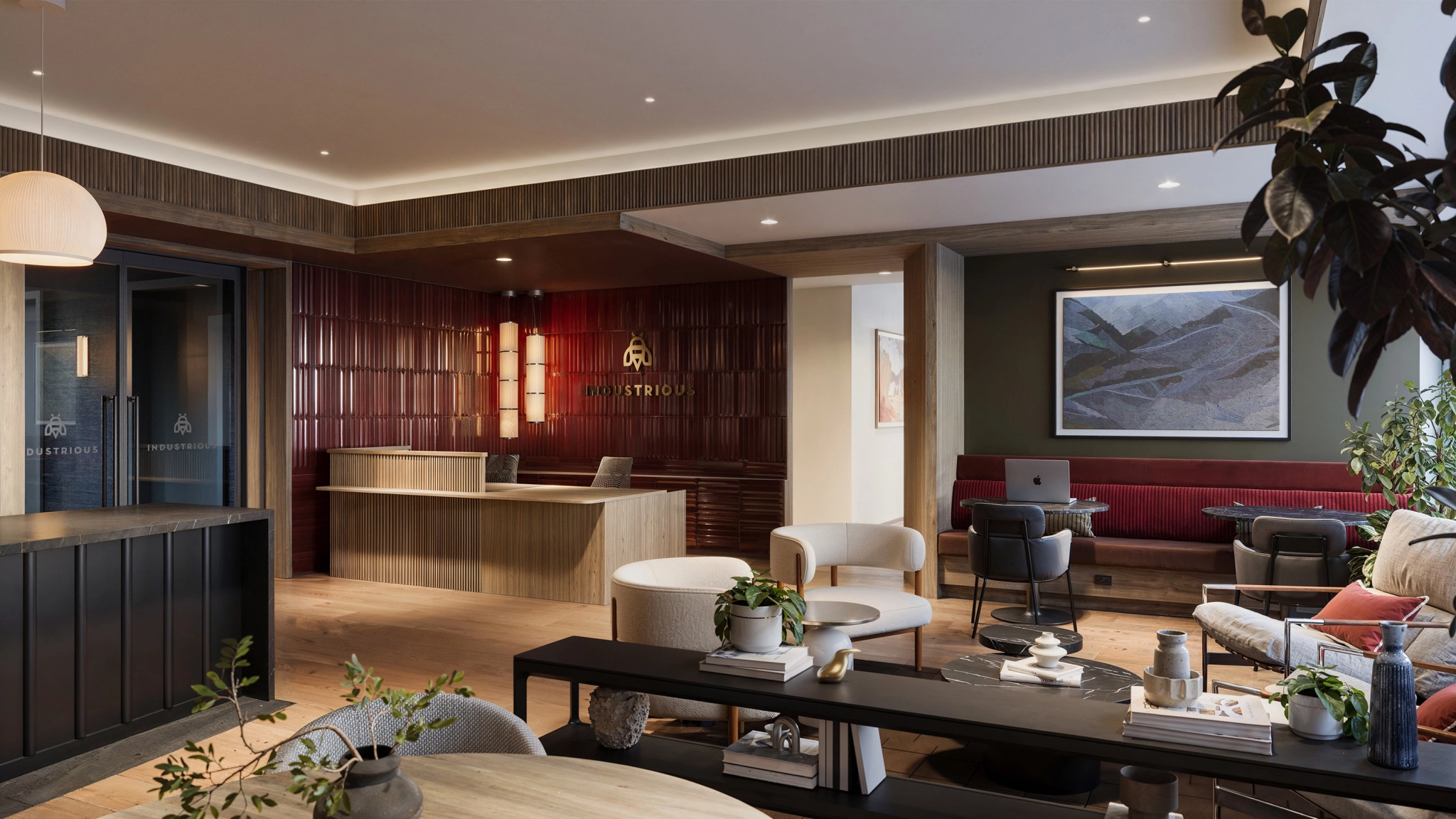 Modern office lobby with a wooden reception desk, red tiled wall, lounge seating, indoor plants, and a landscape painting creates an inviting workspace atmosphere.