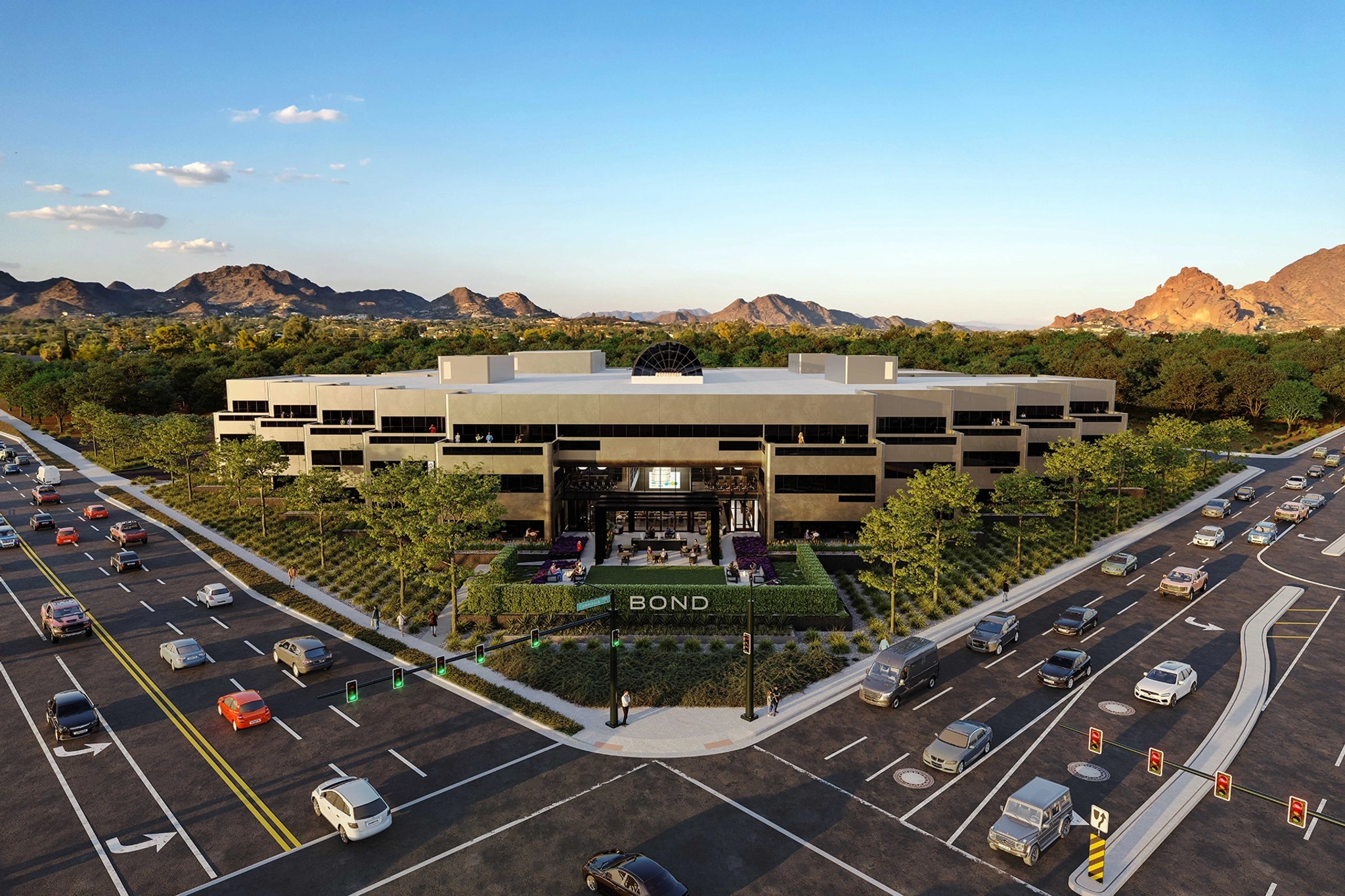 An aerial view of a modern multi-story building labeled "BOND," located at a busy intersection with multiple lanes of traffic and surrounded by greenery and mountains in the background, hints at dynamic coworking spaces inside.