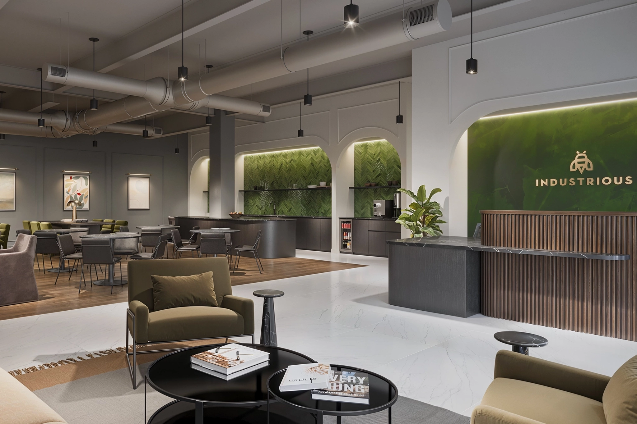 A modern office lounge in Phoenix with seating, tables, and a reception area. Walls display artwork, plants add greenery, and hanging lights illuminate this inviting workspace.