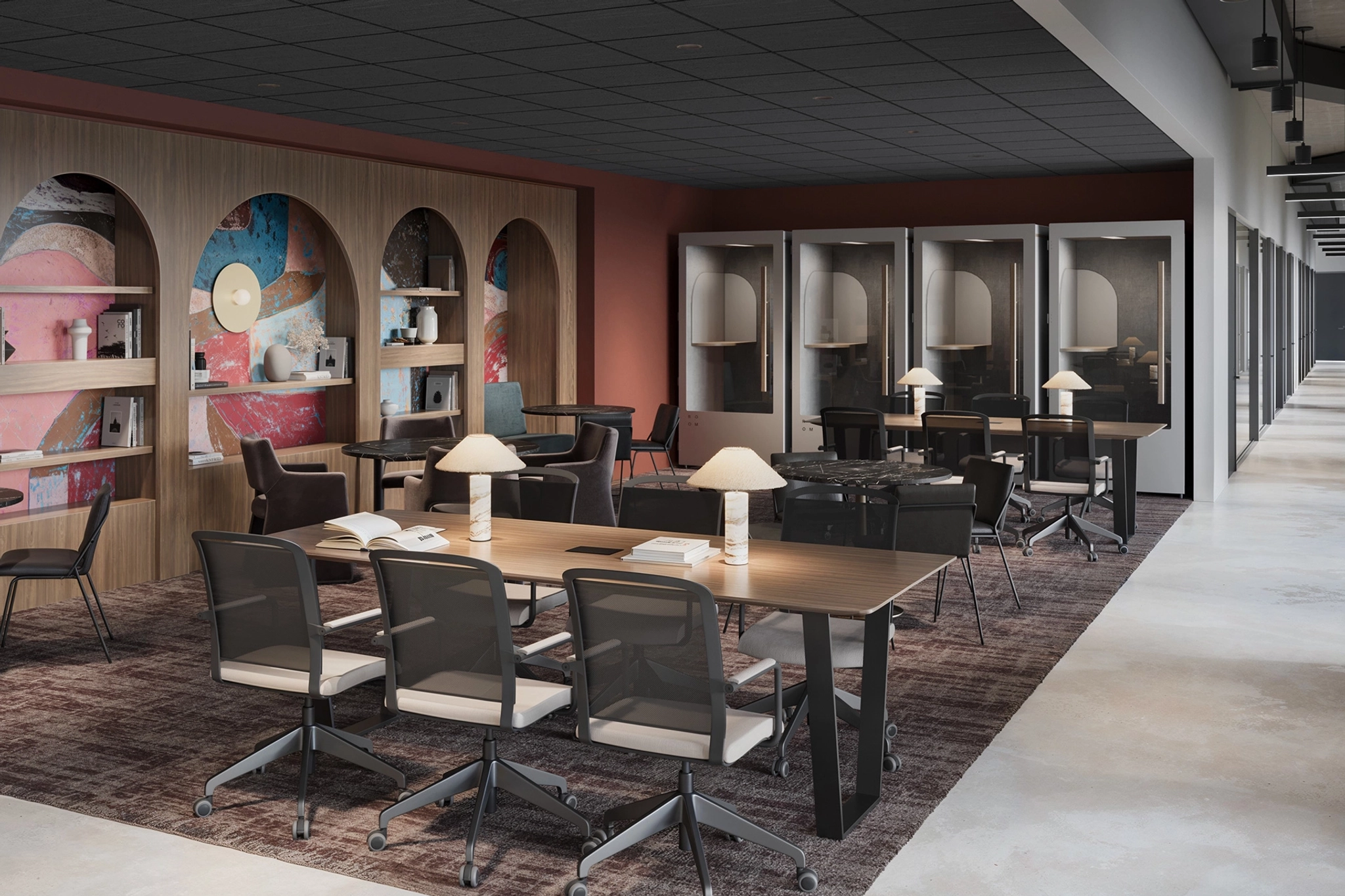 Modern coworking space with open seating, enclosed booths, bookshelves, and decorative wall art. The versatile workspace also features a meeting room to cater to all your professional needs.