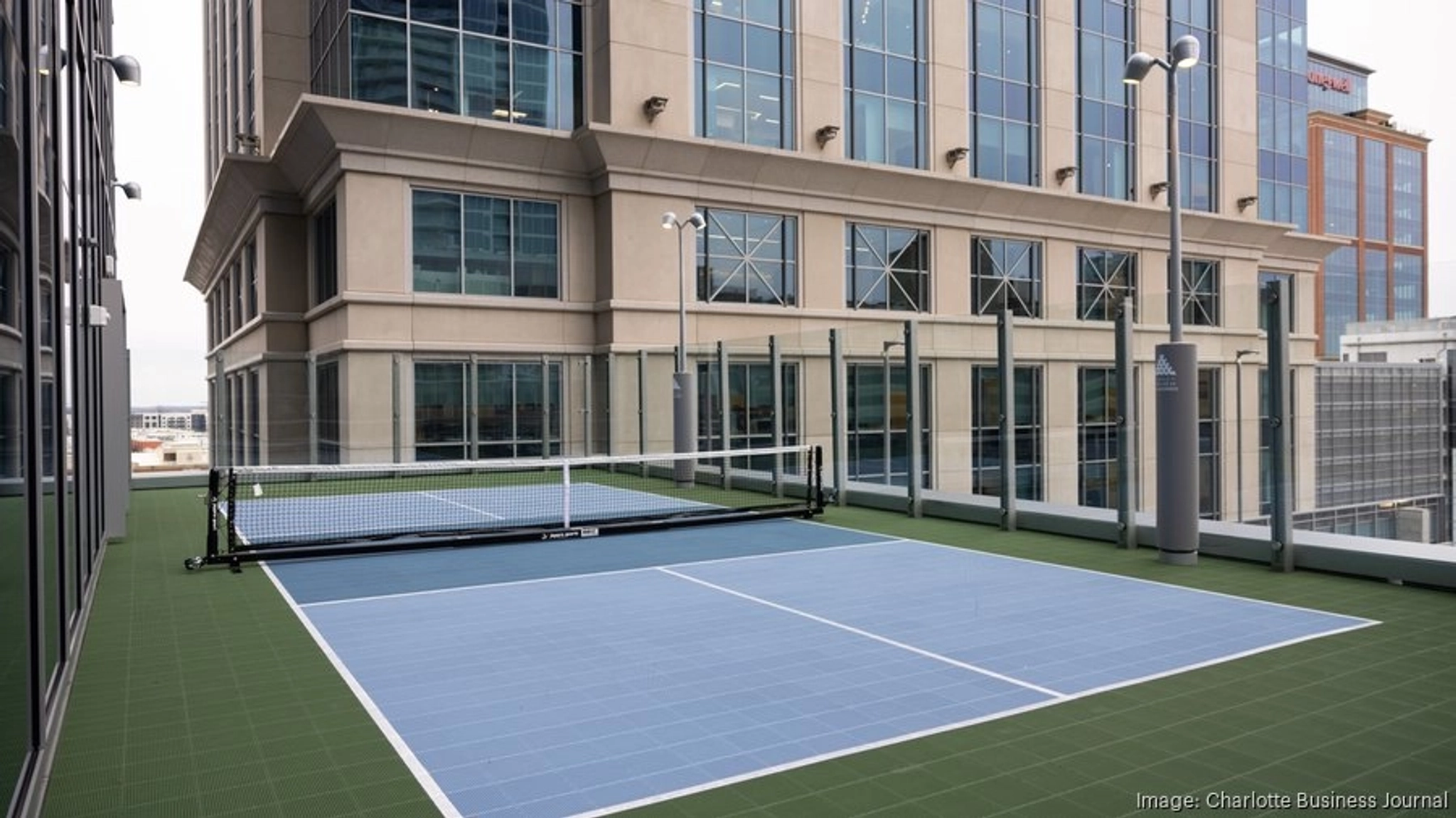 En una azotea de Charlotte, una pista de pickleball está rodeada de altos edificios de oficinas y vallas protectoras.