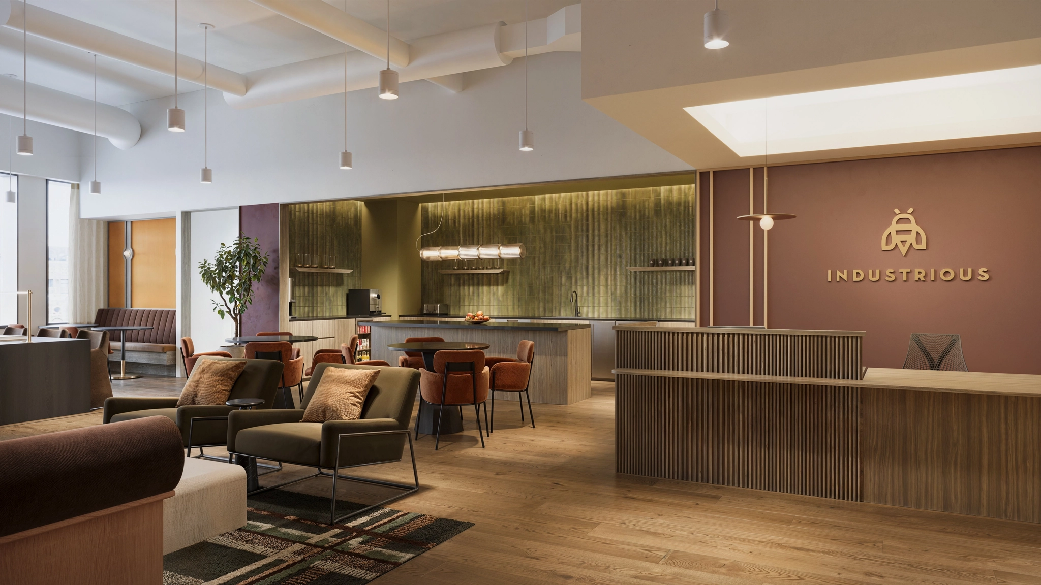 Modern New York coworking lounge with armchairs, a reception desk, a communal table, and a kitchenette; warm lighting and wood finishes throughout; "Industrious" logo on wall. Perfect workspace for productivity and collaboration.