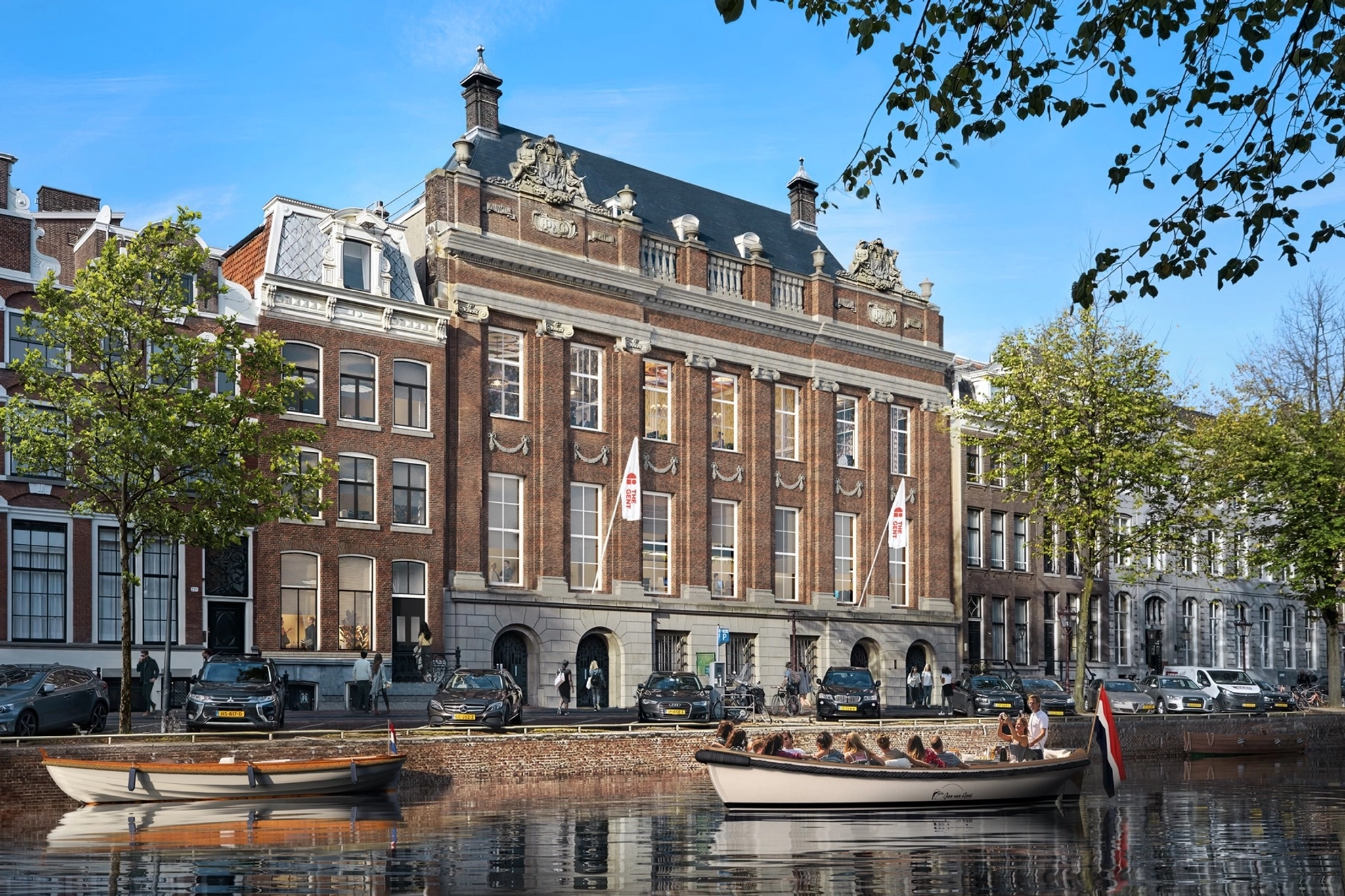 A large historic brick building with ornate details stands by a canal; people ride in boats on the water in front under a clear blue sky. Inside, modern coworking spaces and meeting rooms blend heritage with productivity.