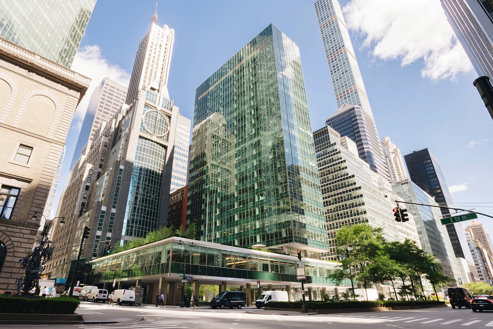 Des immeubles de bureaux modernes en verre et des gratte-ciel bordent une rue très fréquentée de New York, animée par la circulation et les piétons en cette journée ensoleillée, reflétant l'énergie vibrante des espaces de coworking situés à proximité.