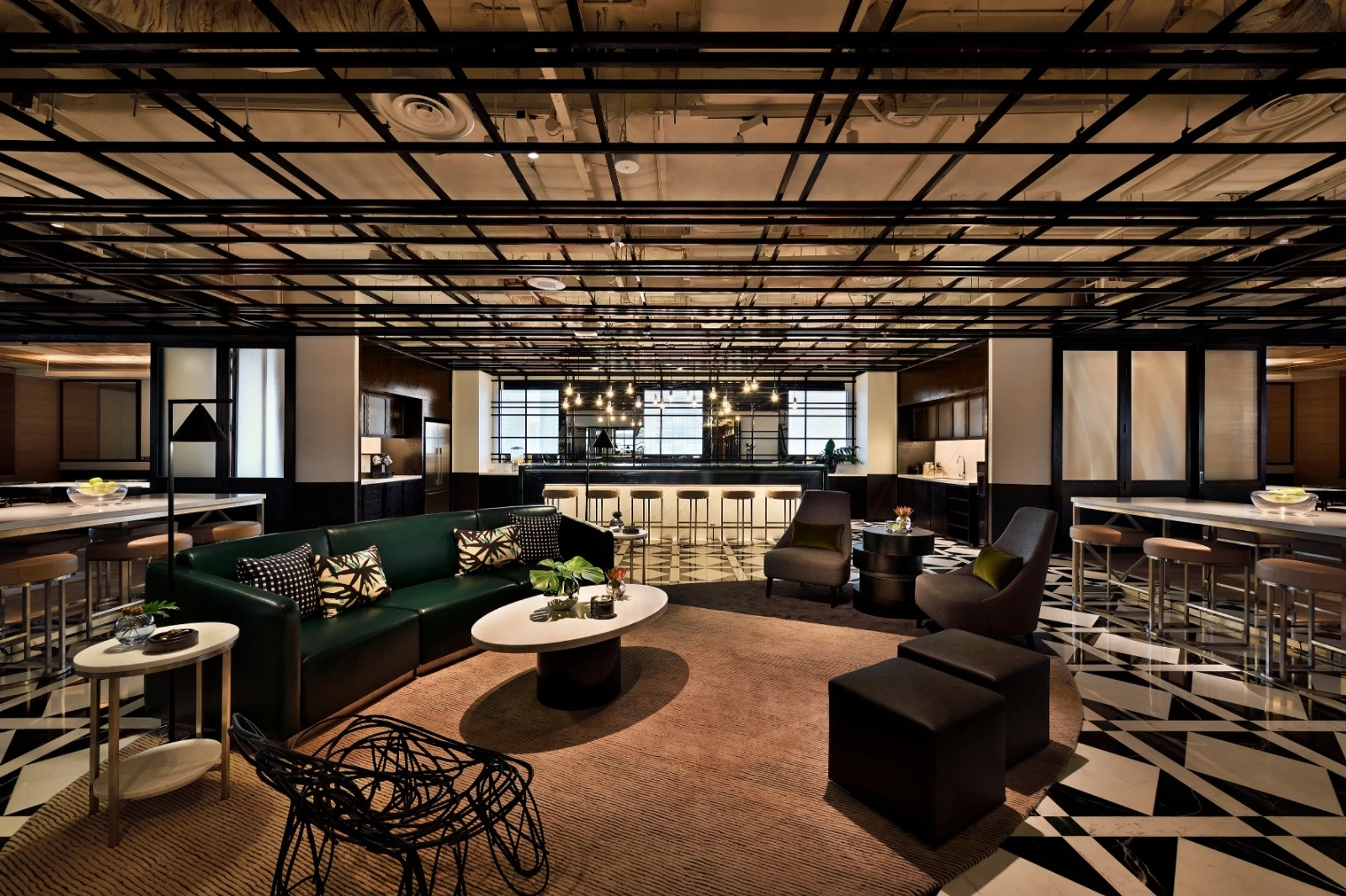 Modern coworking lounge area with geometric flooring, various seating options, round tables, and a central bar in a stylish, open workspace inspired by Singapore’s vibrant interior design.