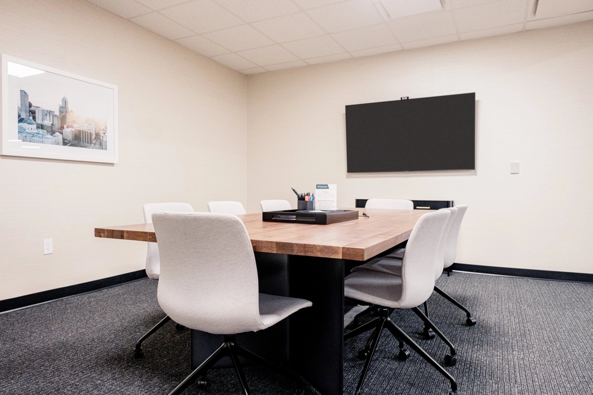 A conference room with a wooden table and chairs, perfect for meetings and office gatherings.