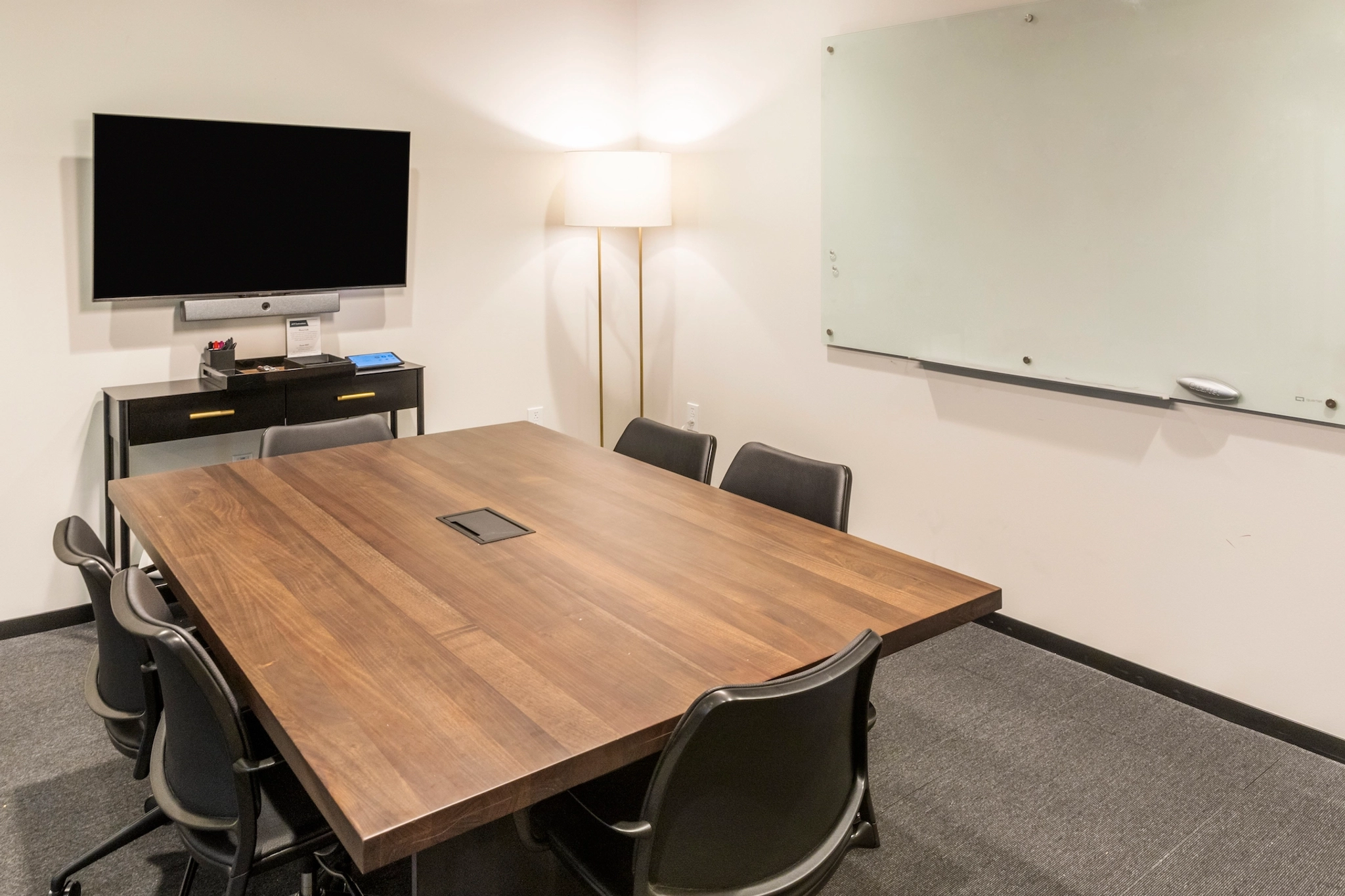 Un bureau/espace de travail avec une table, des chaises et une télévision.