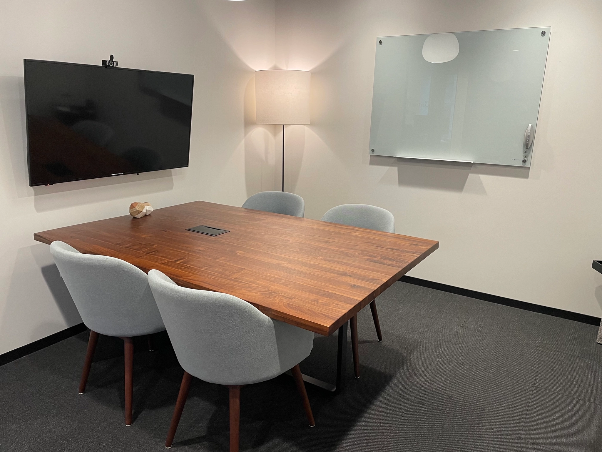 A meeting room with a table and chairs, equipped with a TV.