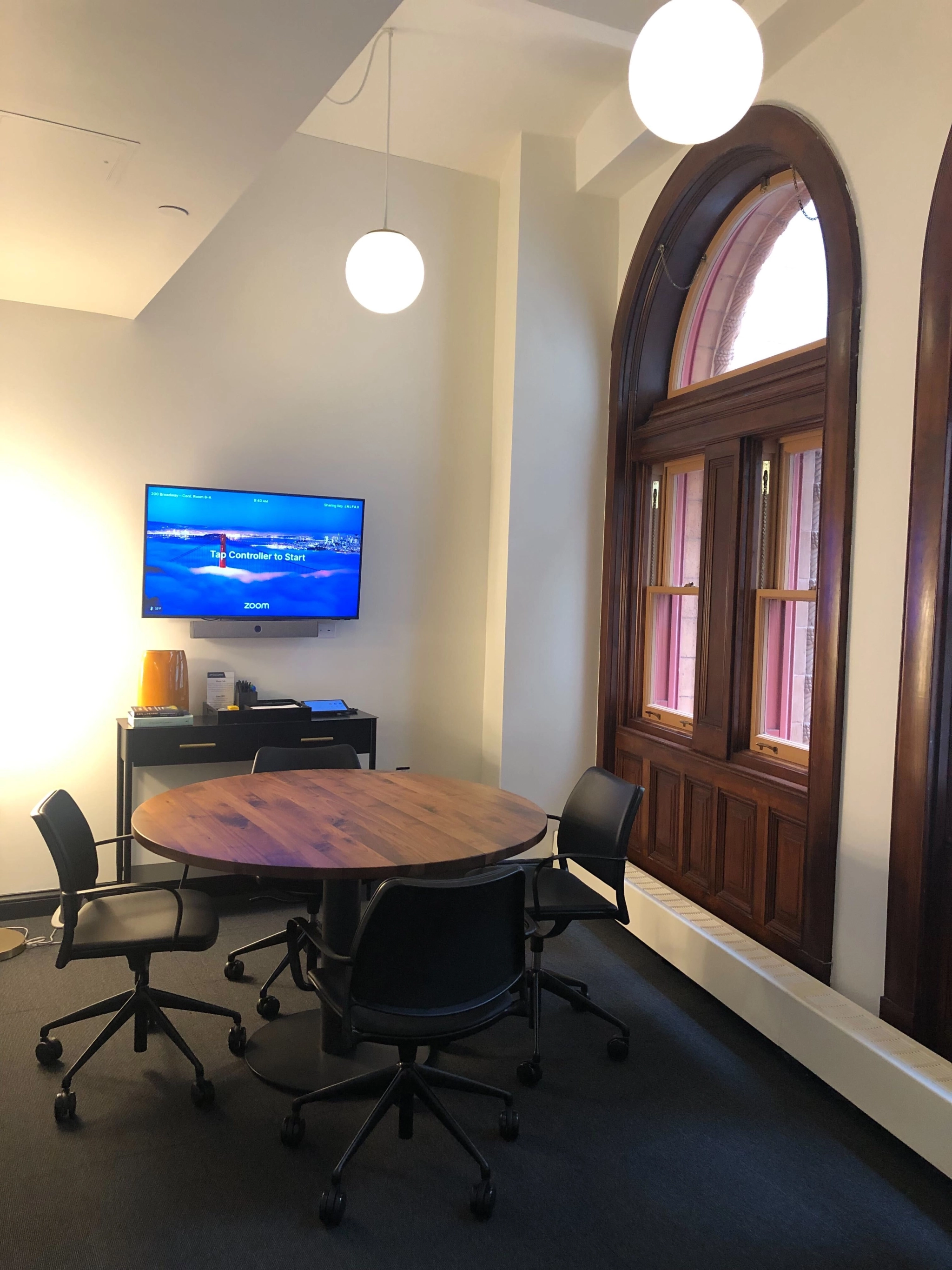 Een coworking-vergaderruimte met een ronde tafel, stoelen en een televisie.