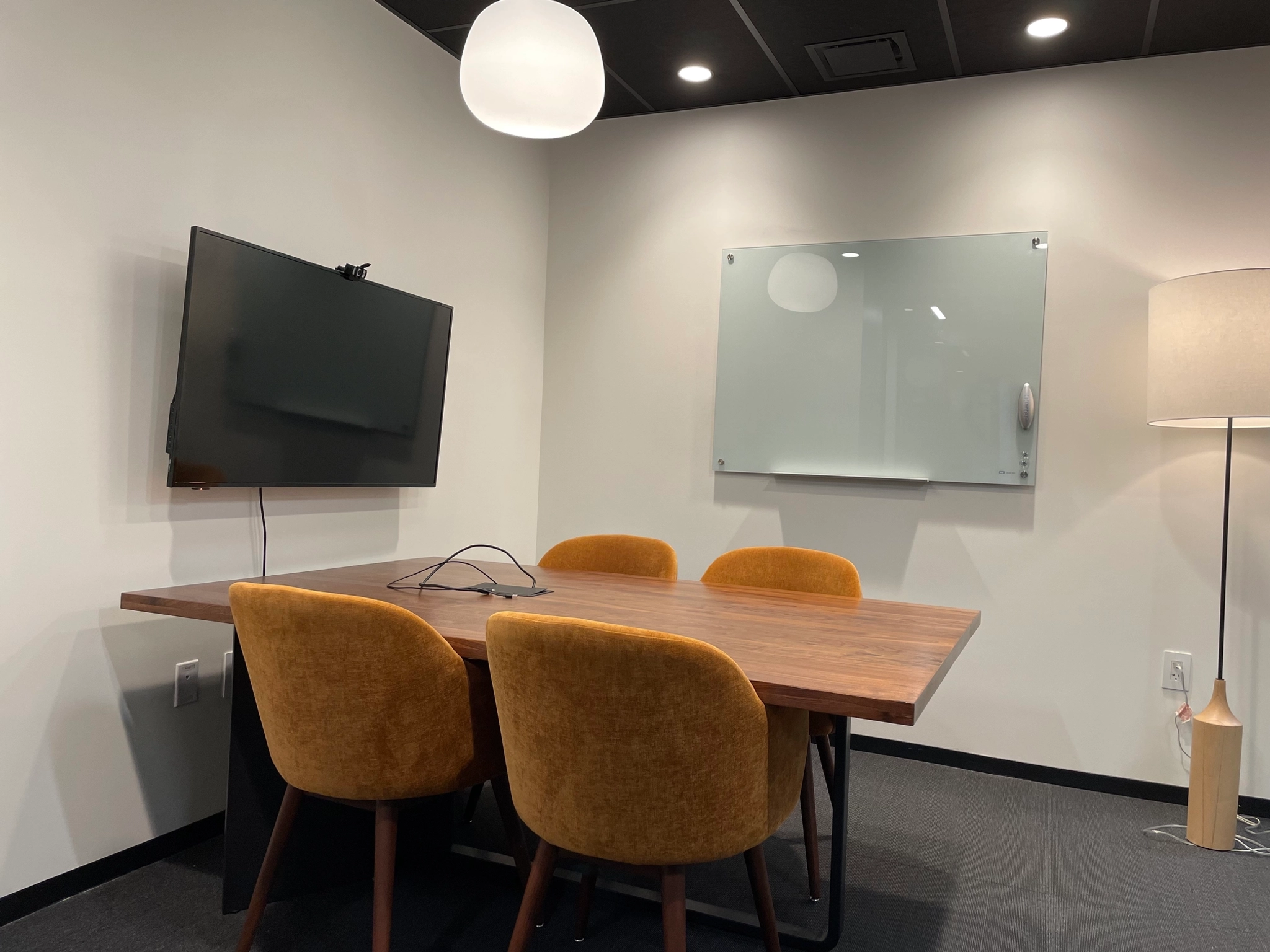 Une salle de conférence avec table et chaises, équipée d'une télévision, adaptée au coworking du bureau de Washington.