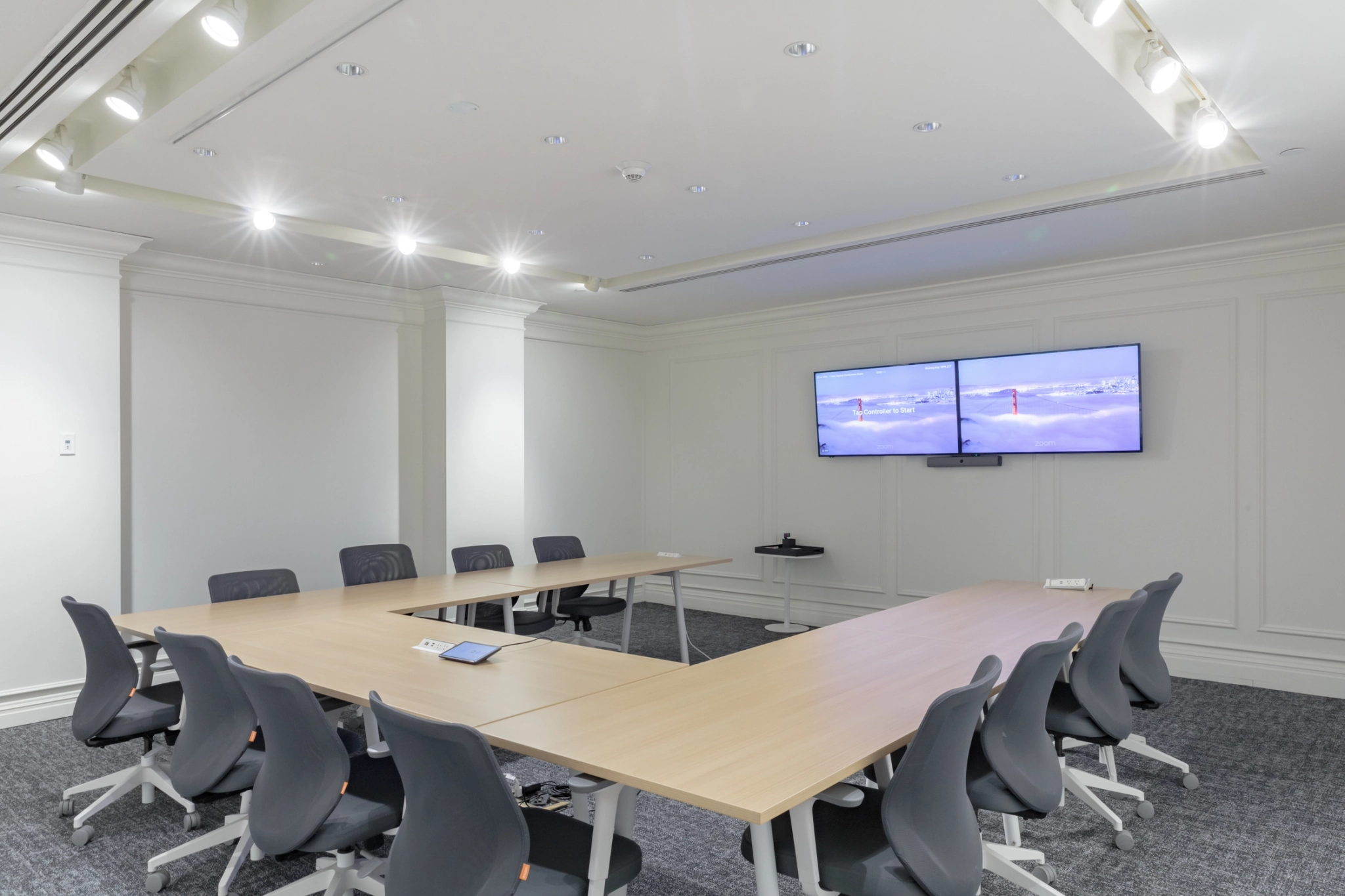 A meeting room with a TV on the wall optimized for coworking individuals or teams in need of a versatile workspace.