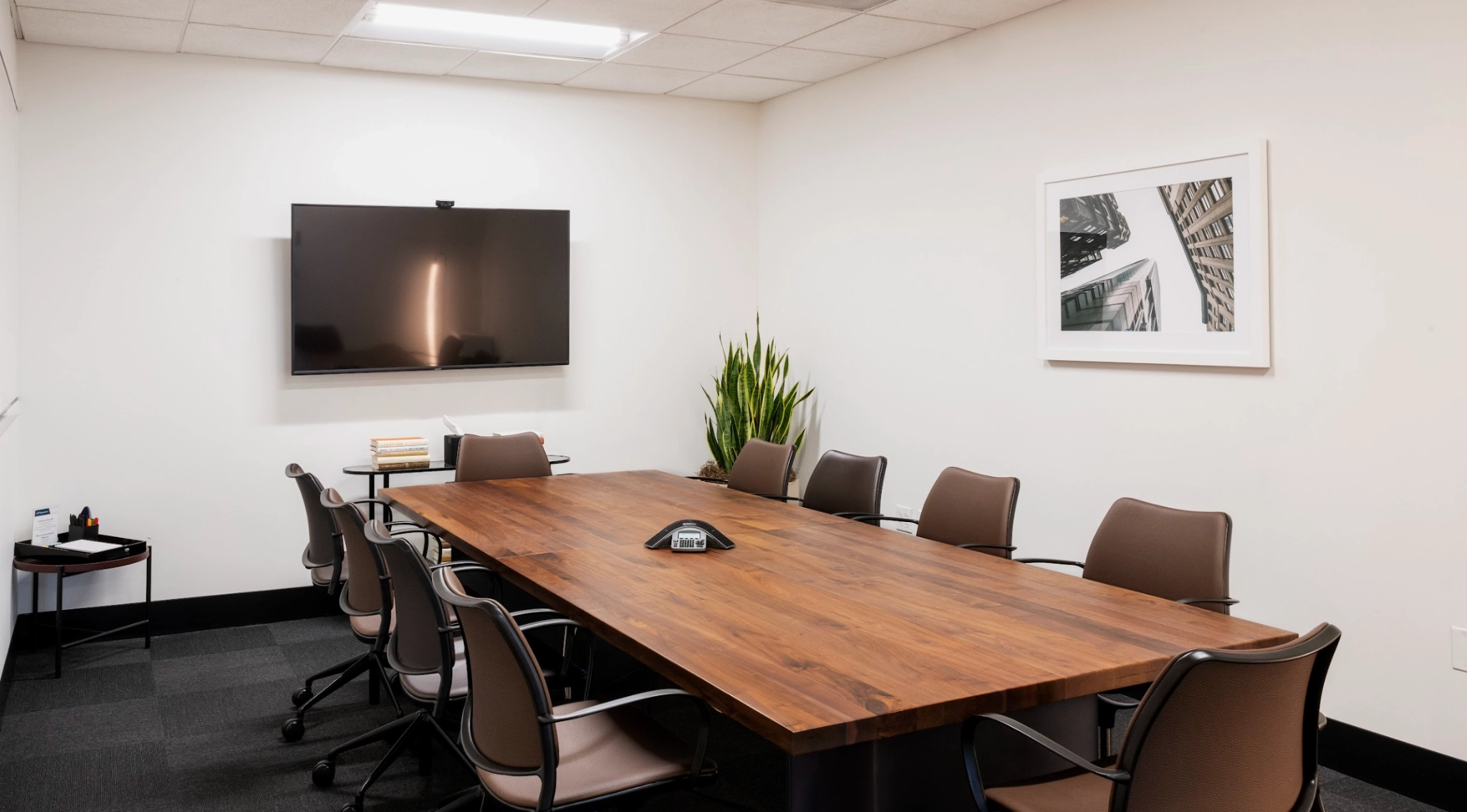 Een coworking-vergaderruimte in Boston ingericht met een houten tafel en stoelen.