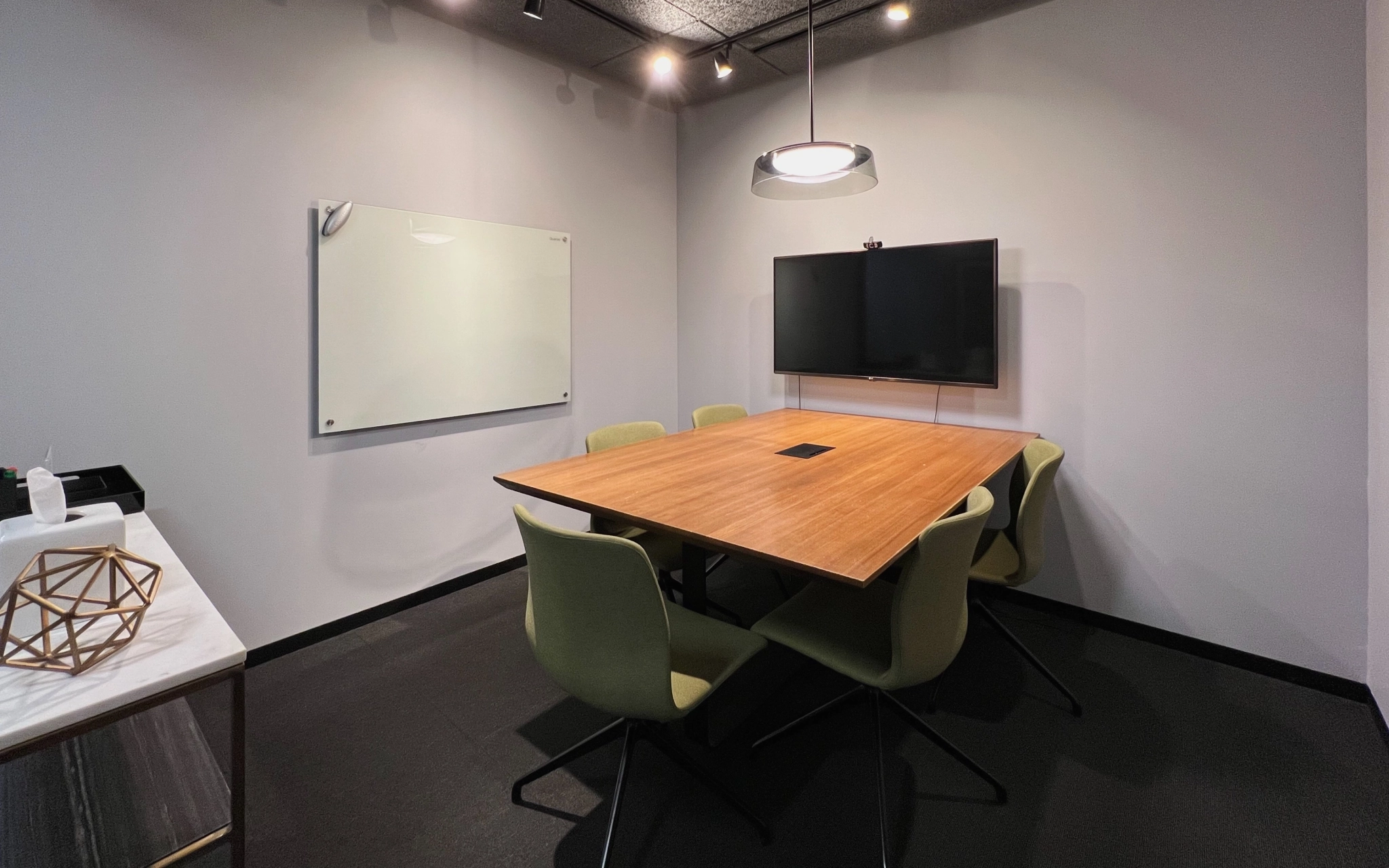 A coworking space in Minneapolis equipped with a table, chairs, and a TV for collaborative meetings and presentations.