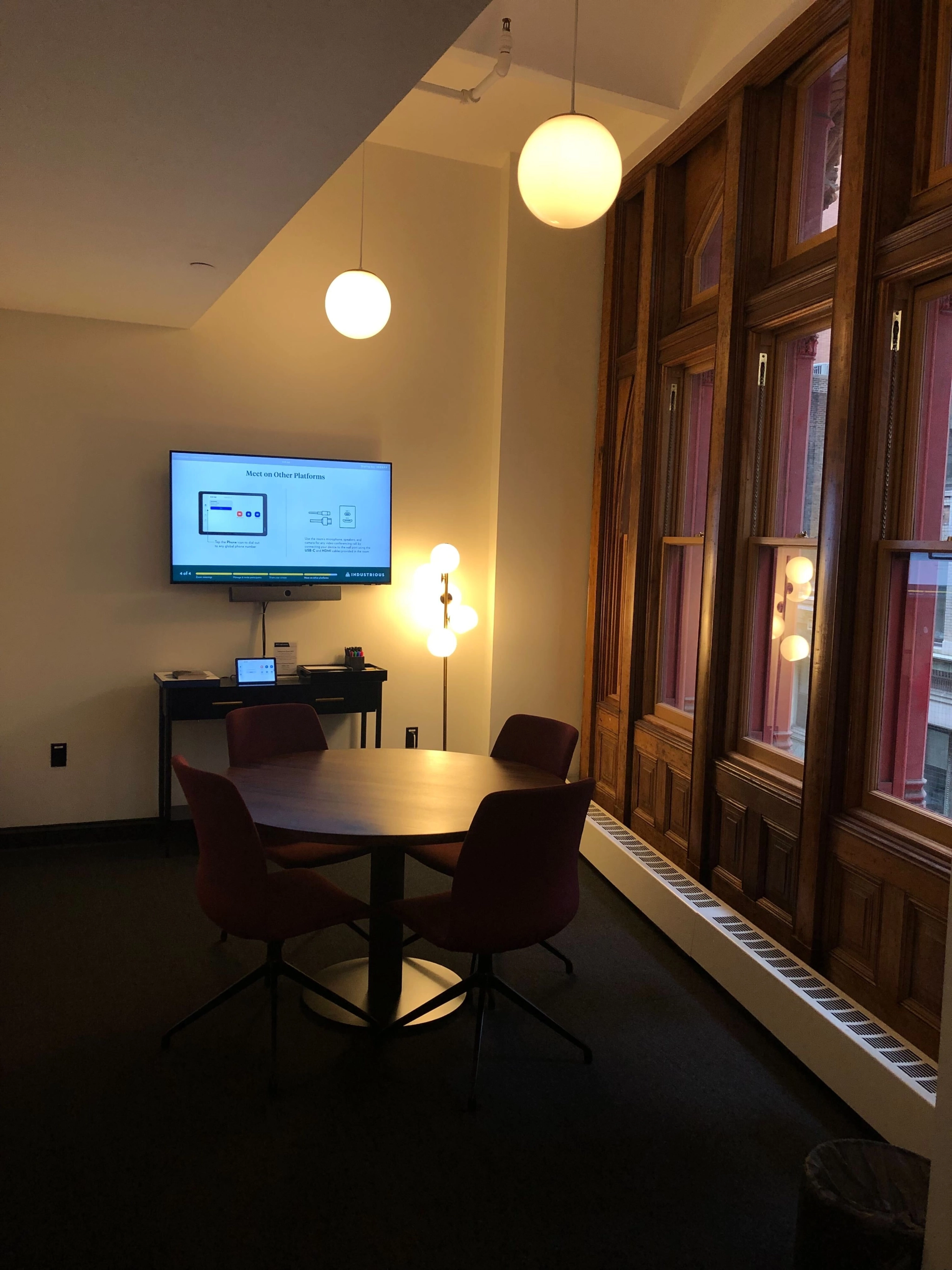 Un bureau de coworking avec table et chaises pour réunions, équipé d'une télévision.