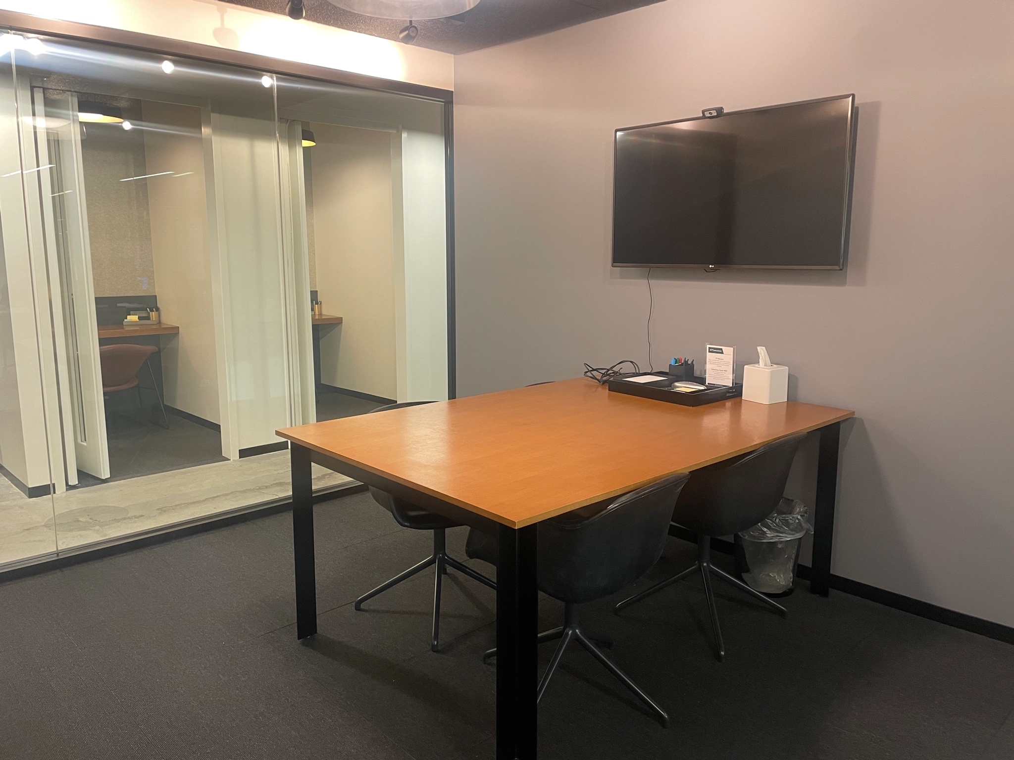 A meeting room with a table, chairs and a TV.