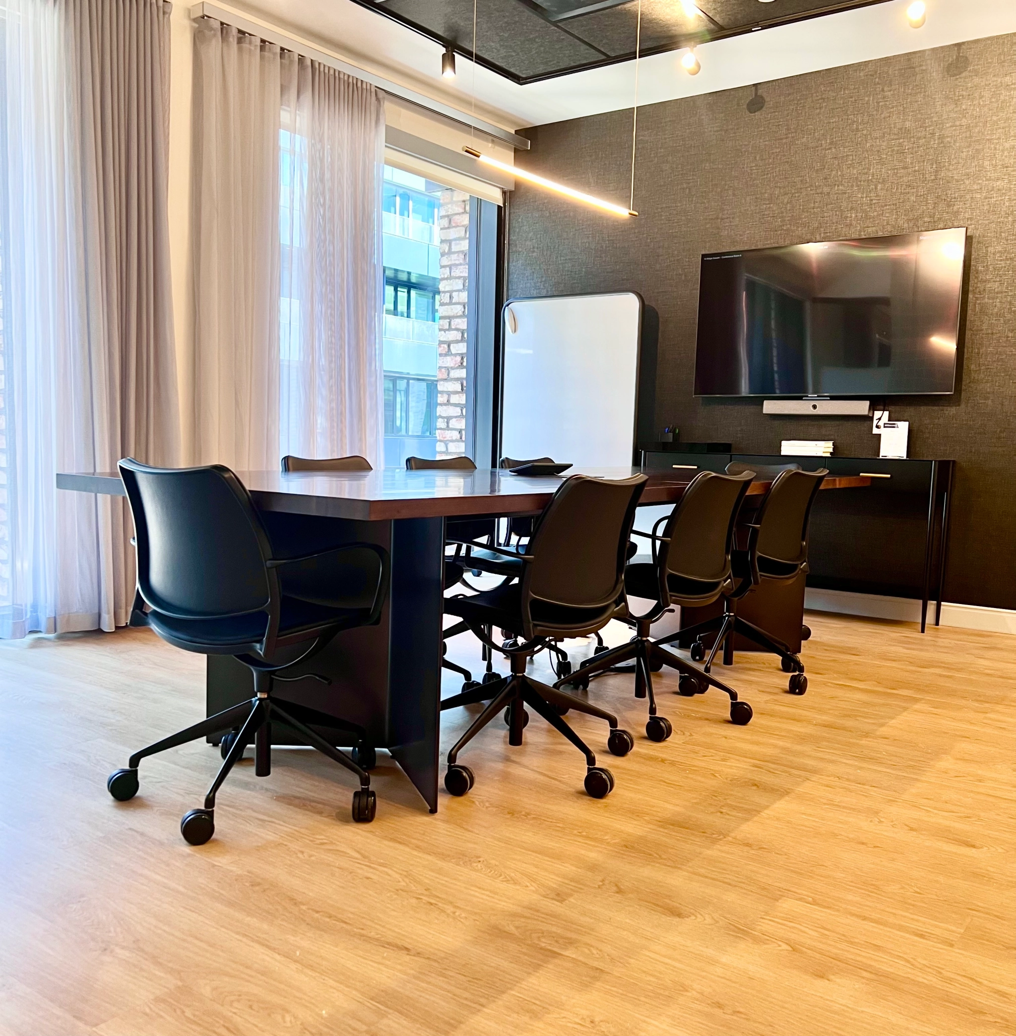 Une salle de conférence avec une table et des chaises noires qui sert d'espace de travail ou de bureau pour des discussions collaboratives.