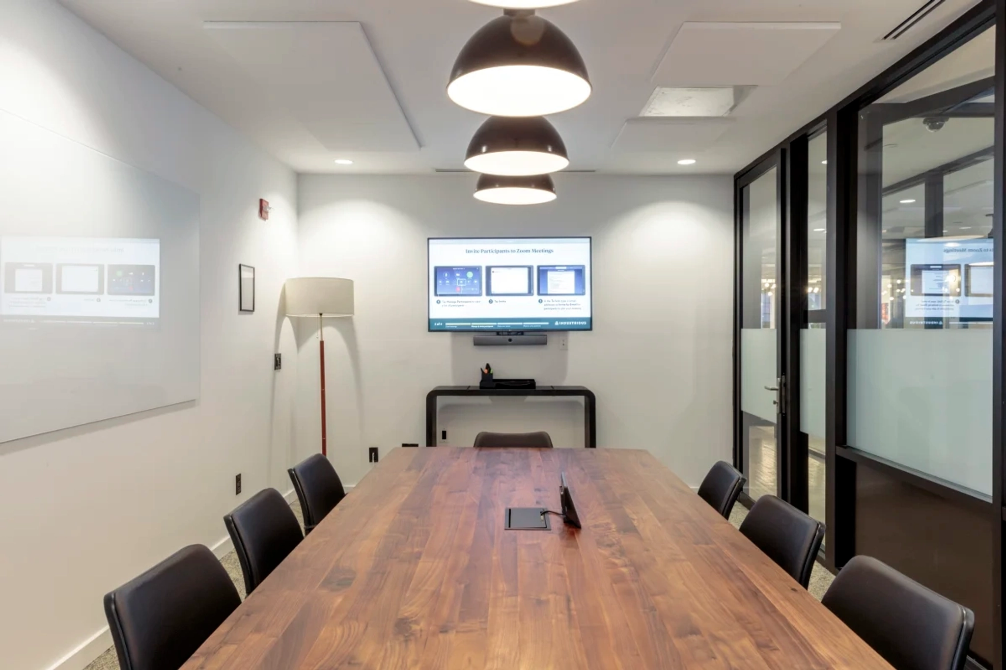 A coworking meeting room with a wooden table and TV.