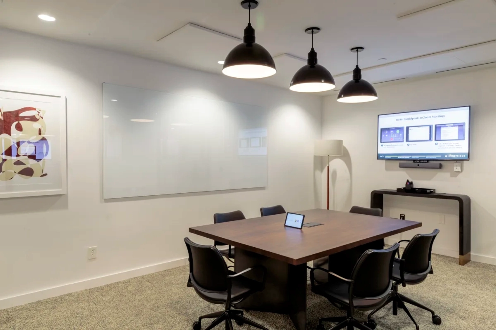 An office meeting room with a table, chairs, and a TV.