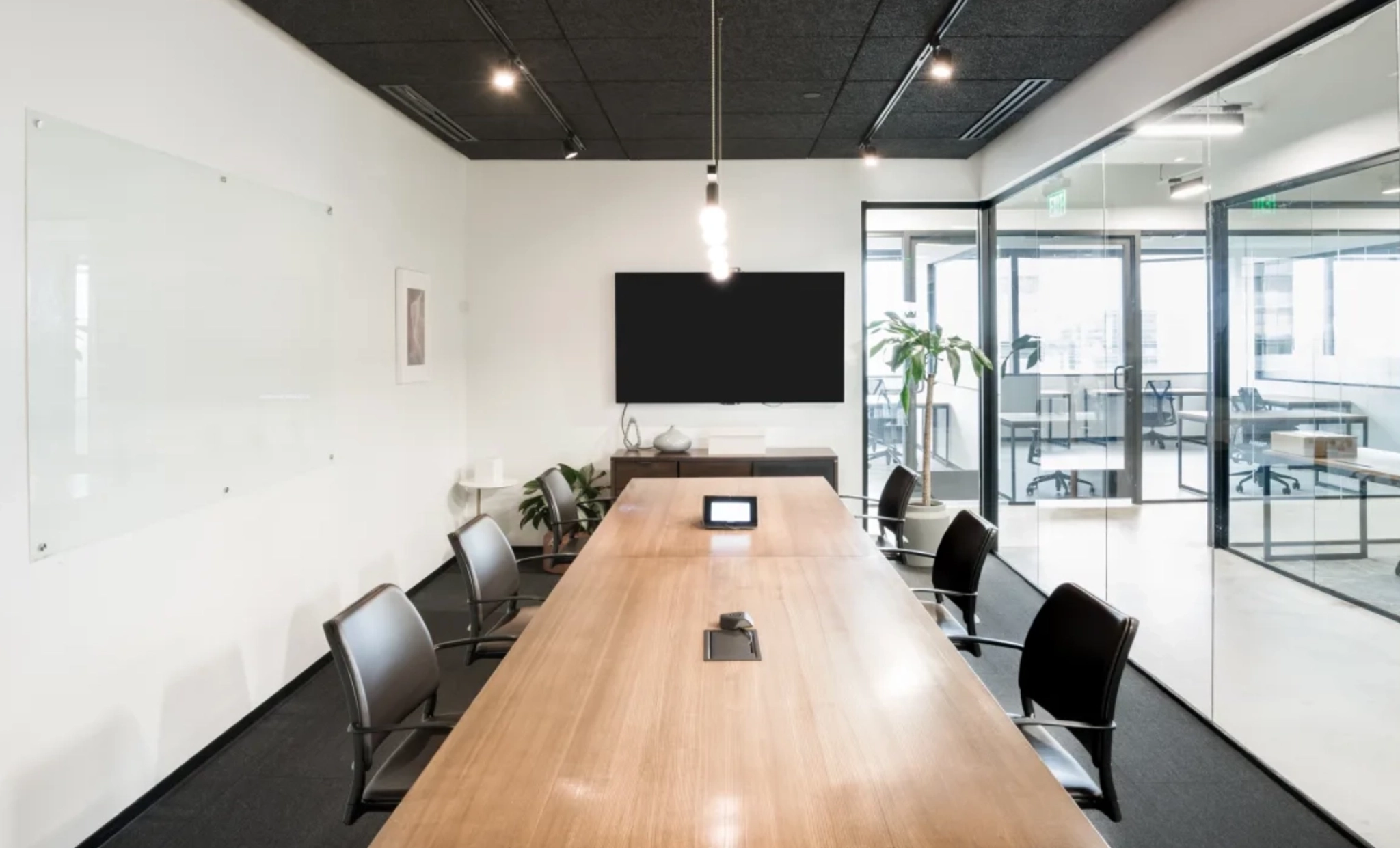 Een kantoorvergaderruimte met een houten tafel en stoelen.