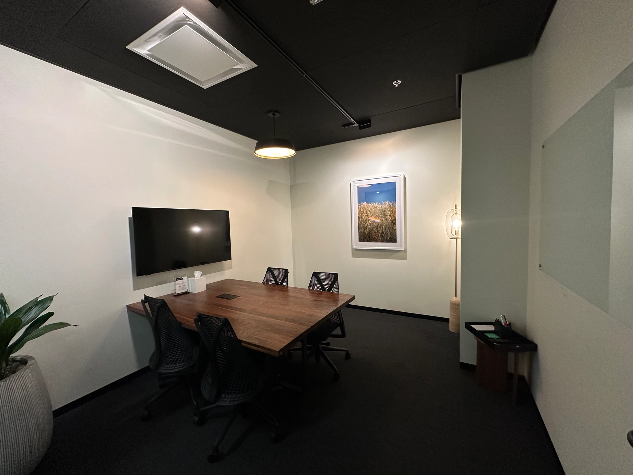 A meeting room with a table, chairs, and a TV.