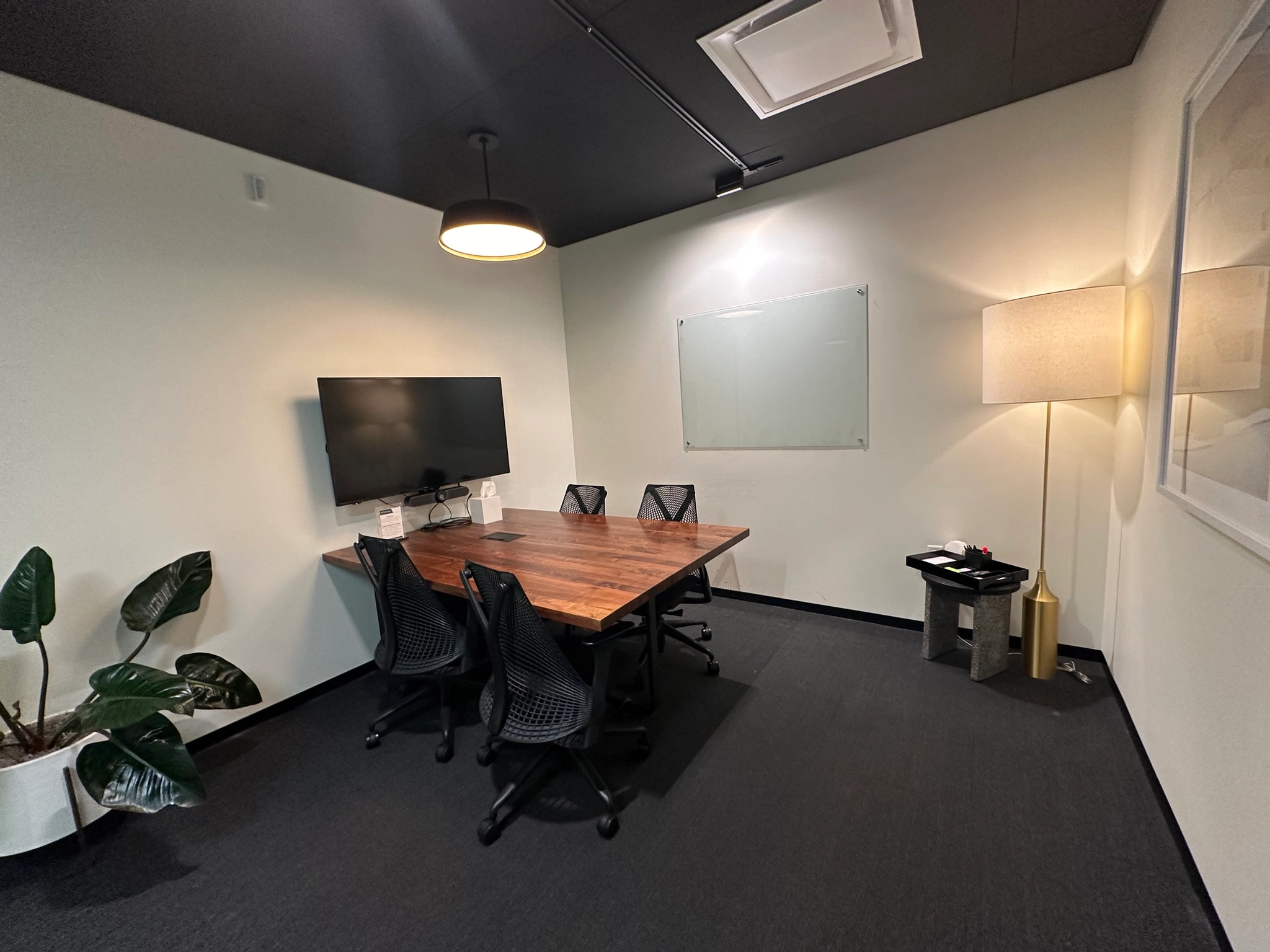 Une salle de réunion de coworking à Costa Mesa équipée d'une table, de chaises et d'une télévision.