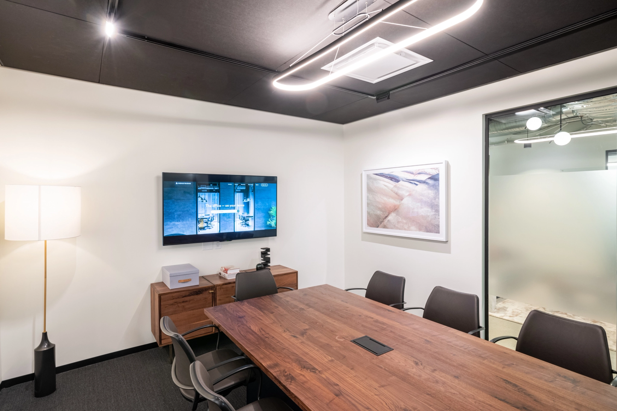 Un espace de travail de coworking à Costa Mesa avec une table en bois et une télévision.