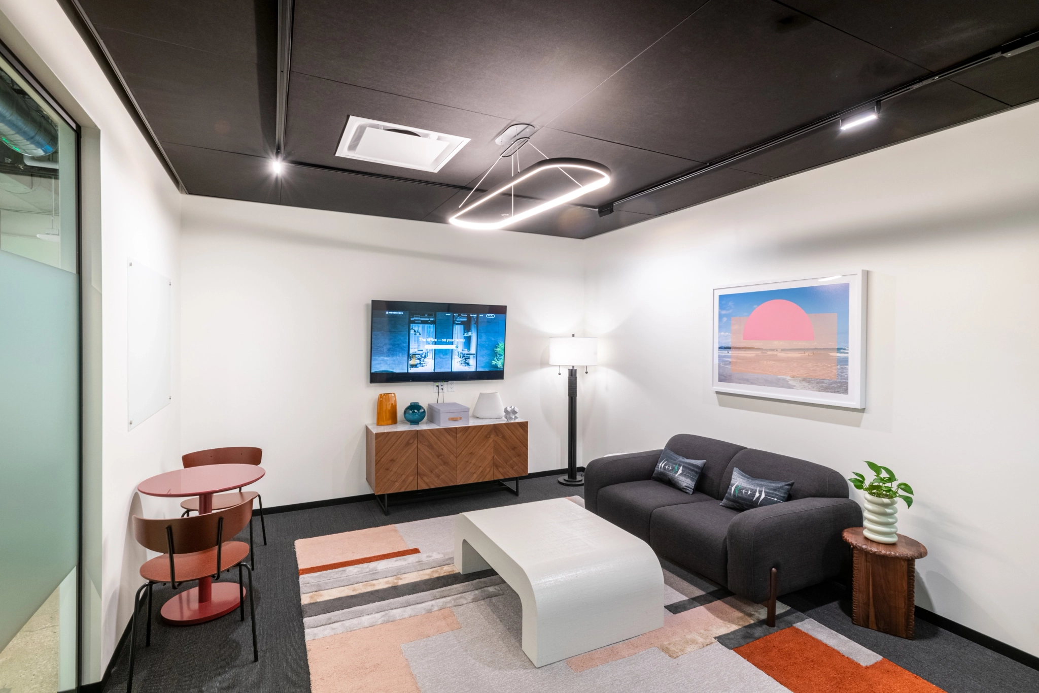 A coworking office with modern couches and a TV in the meeting room.