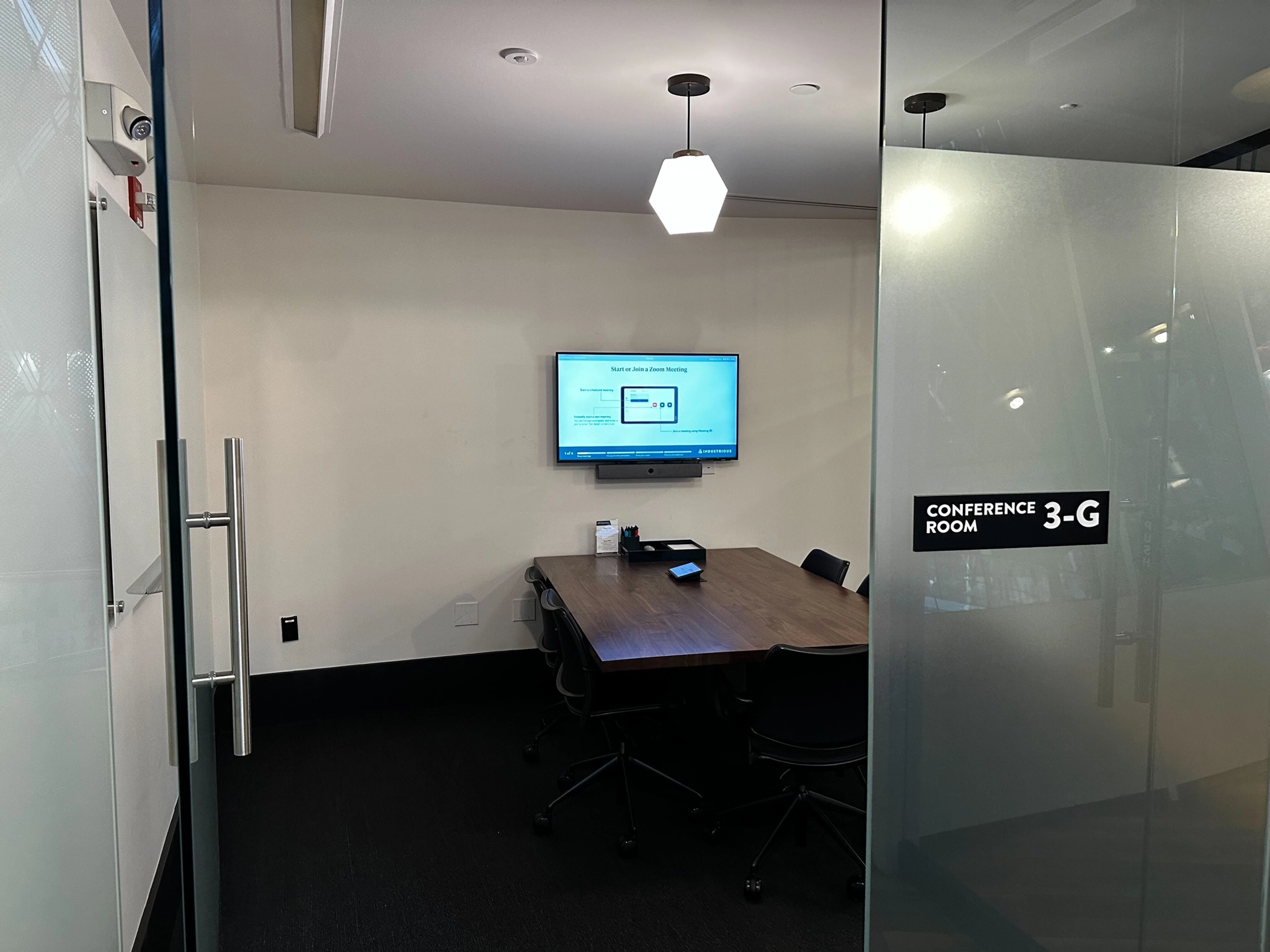 A modern workspace in New York outfitted with glass doors and a sleek TV for office meetings.