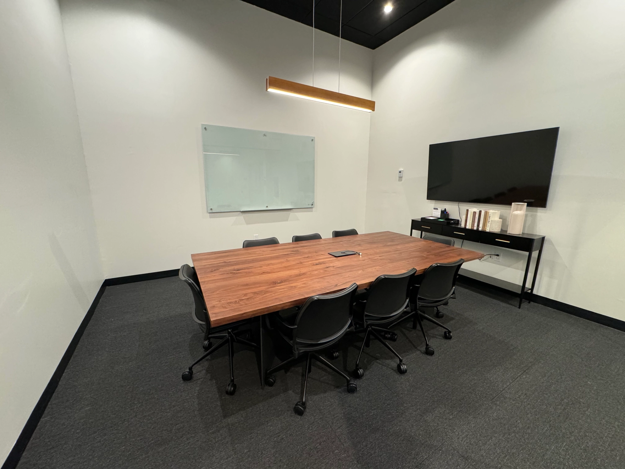 A coworking meeting room with a wooden table and chairs in an office setting.