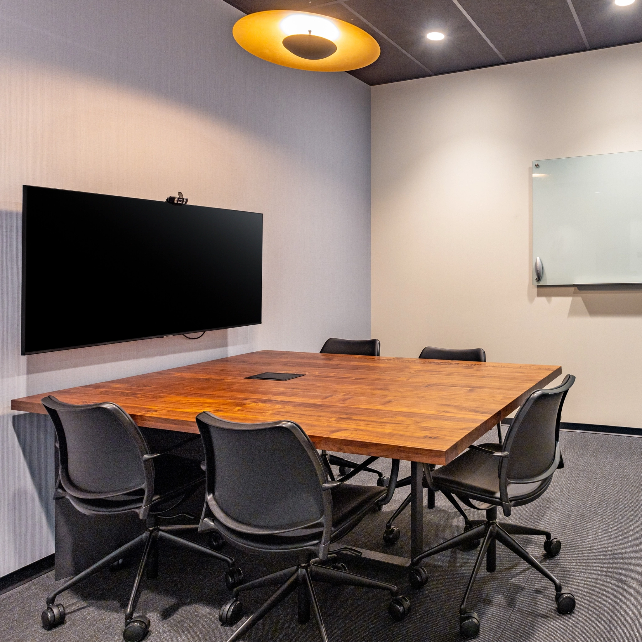 Salle de conférence à Washington avec une table en bois, six chaises, une télévision murale, un tableau blanc et un plafonnier circulaire ; parfait pour le coworking et les réunions.