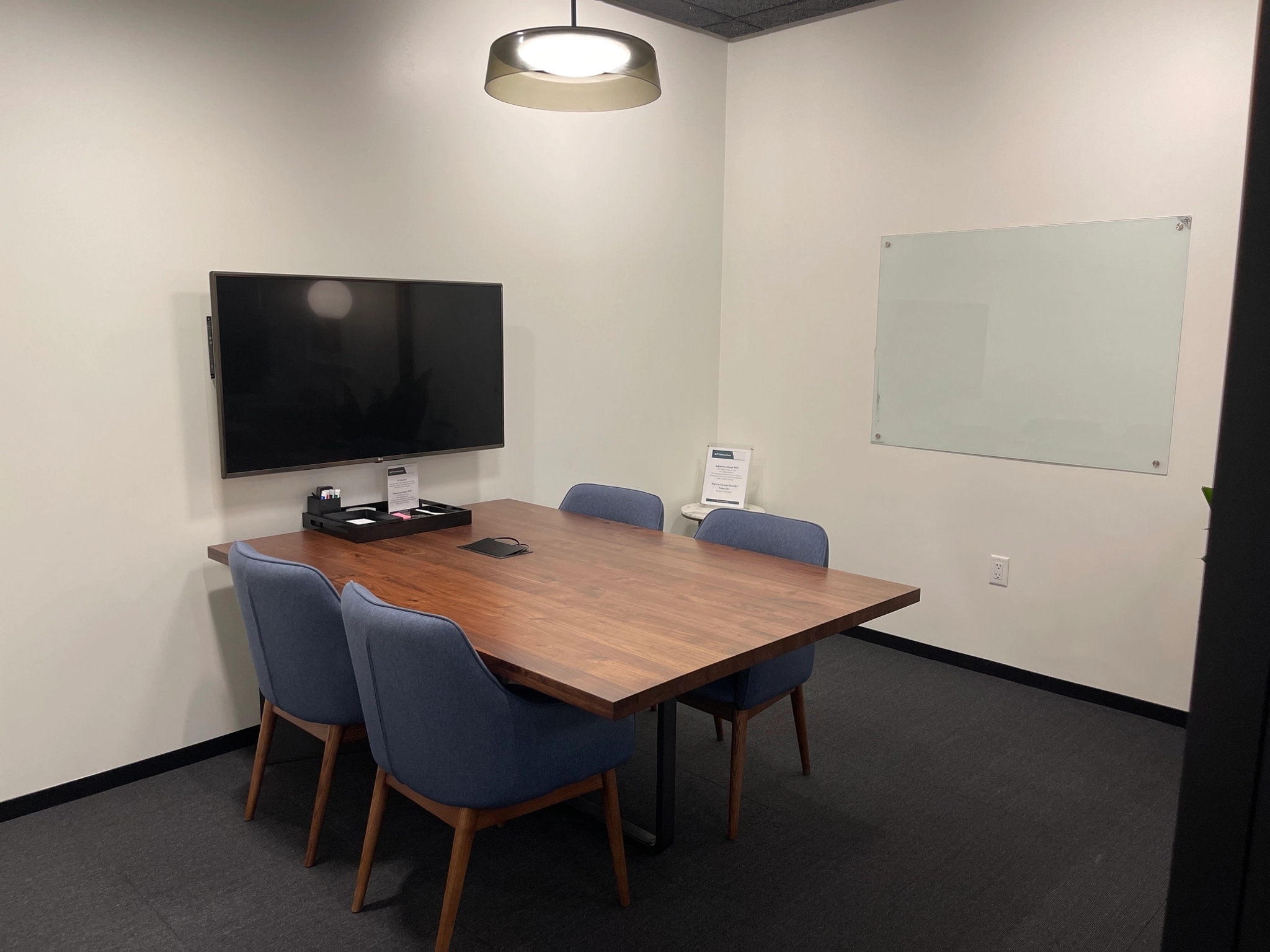 A coworking meeting room equipped with a table and chairs for collaborative work, as well as a TV for presentations.